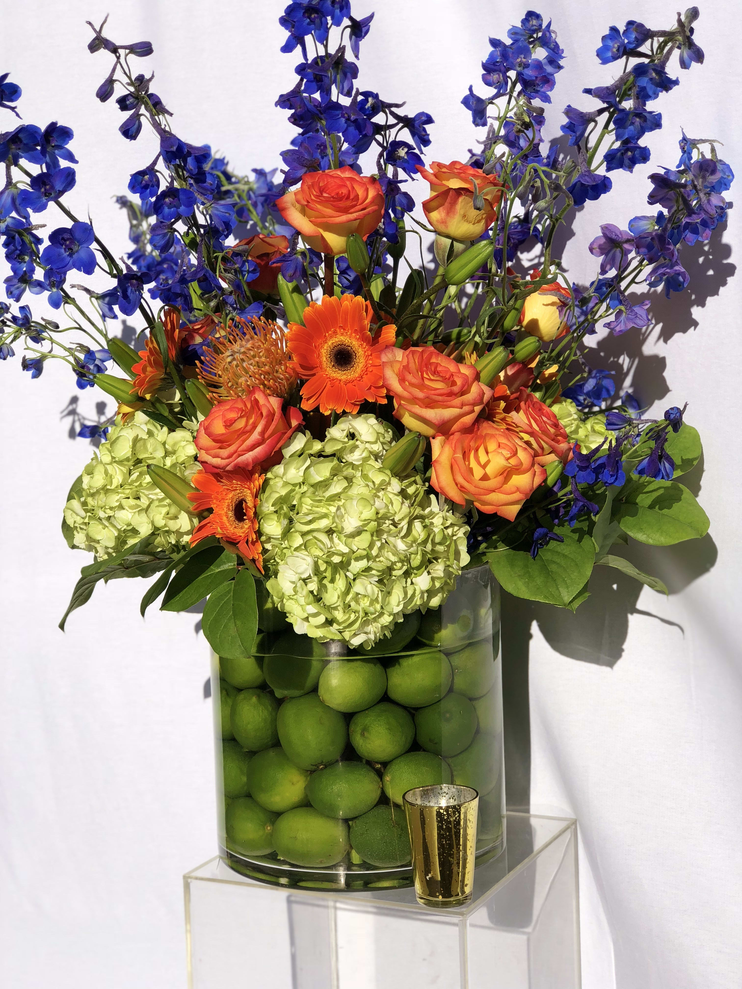 Orange roses and gerbera daisies in a vase with blue flowers