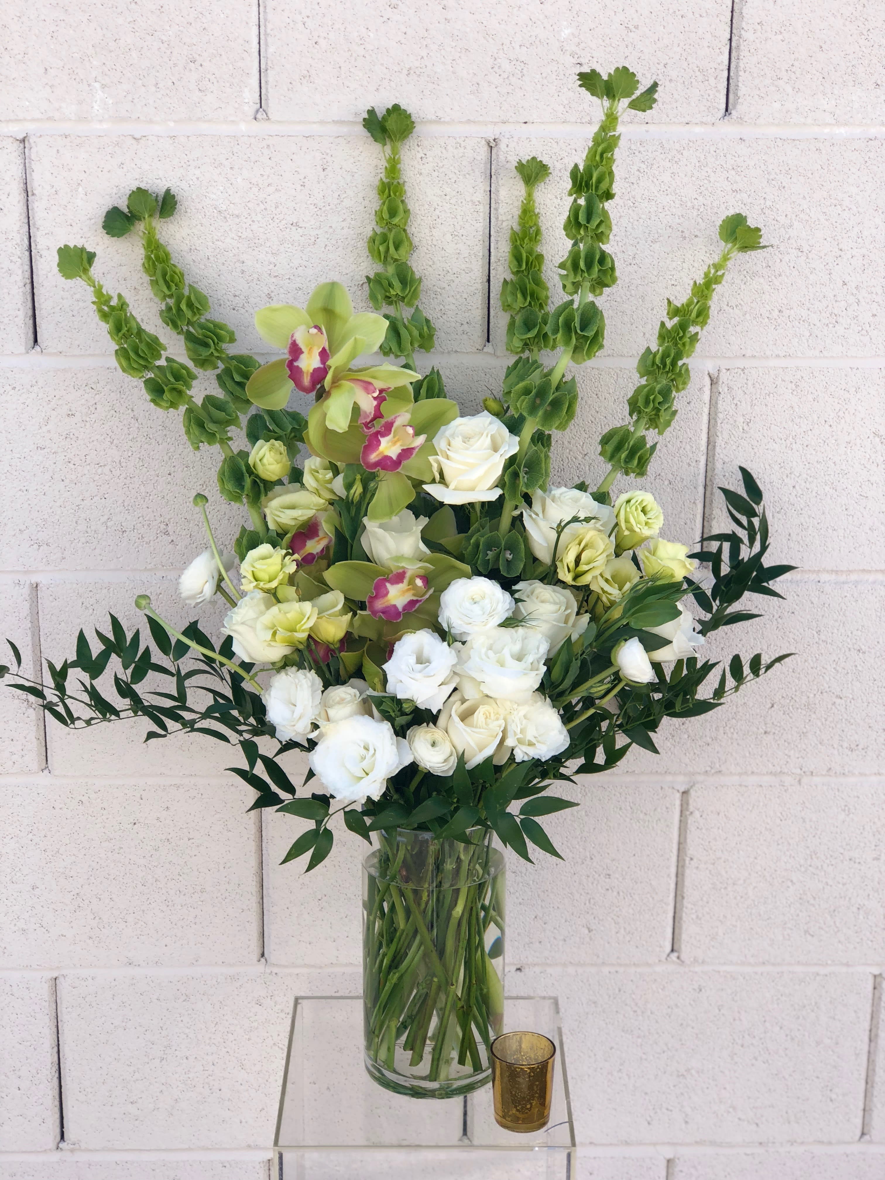 White and pale green floral arrangement in a clear glass vase