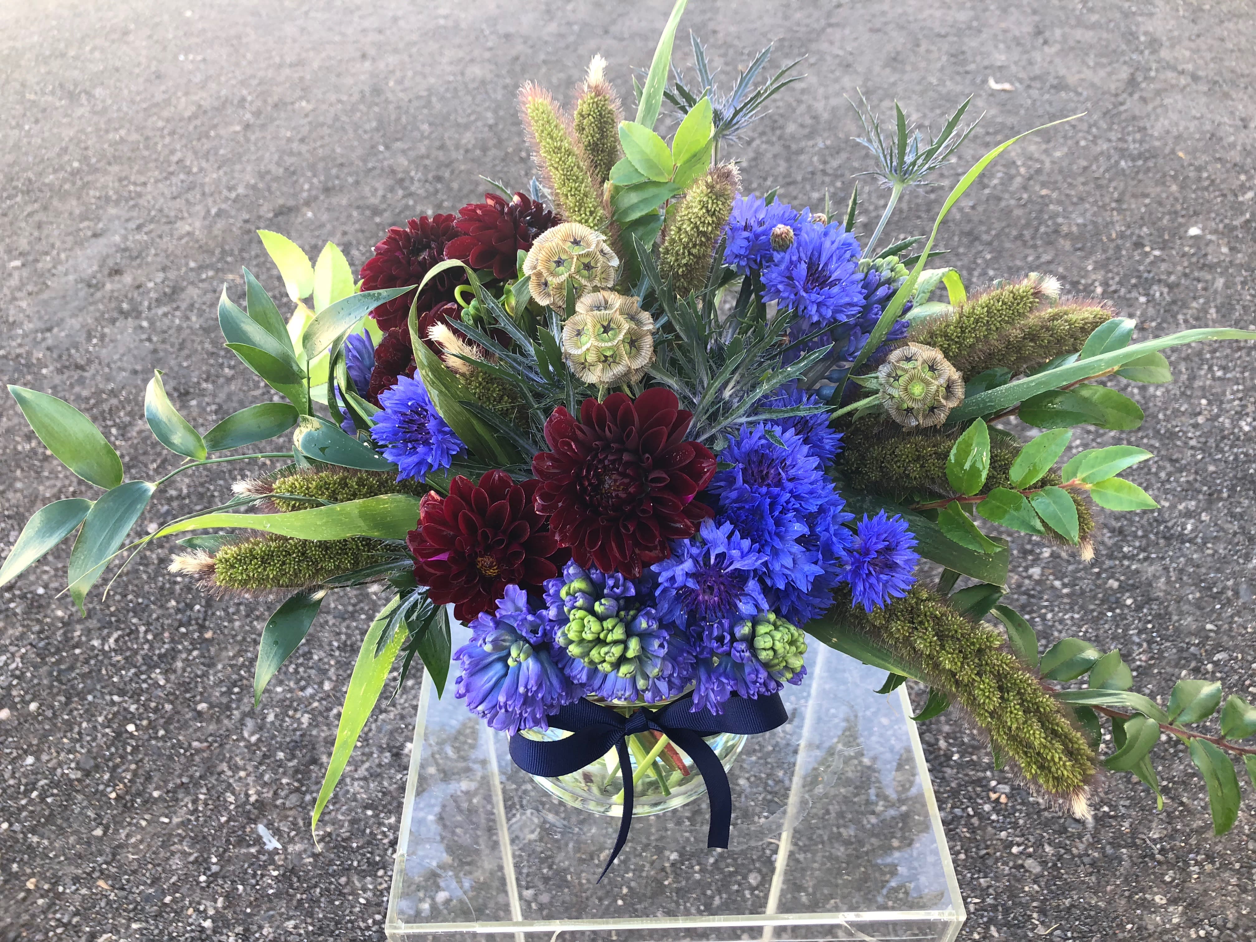 Mr. Nice Guy  - This arrangement is made up of various textural and seasonal elements. This is the perfect gift for ( or from)  Mr. Nice Guy. This may include various dark toned florals and varied greenery. 