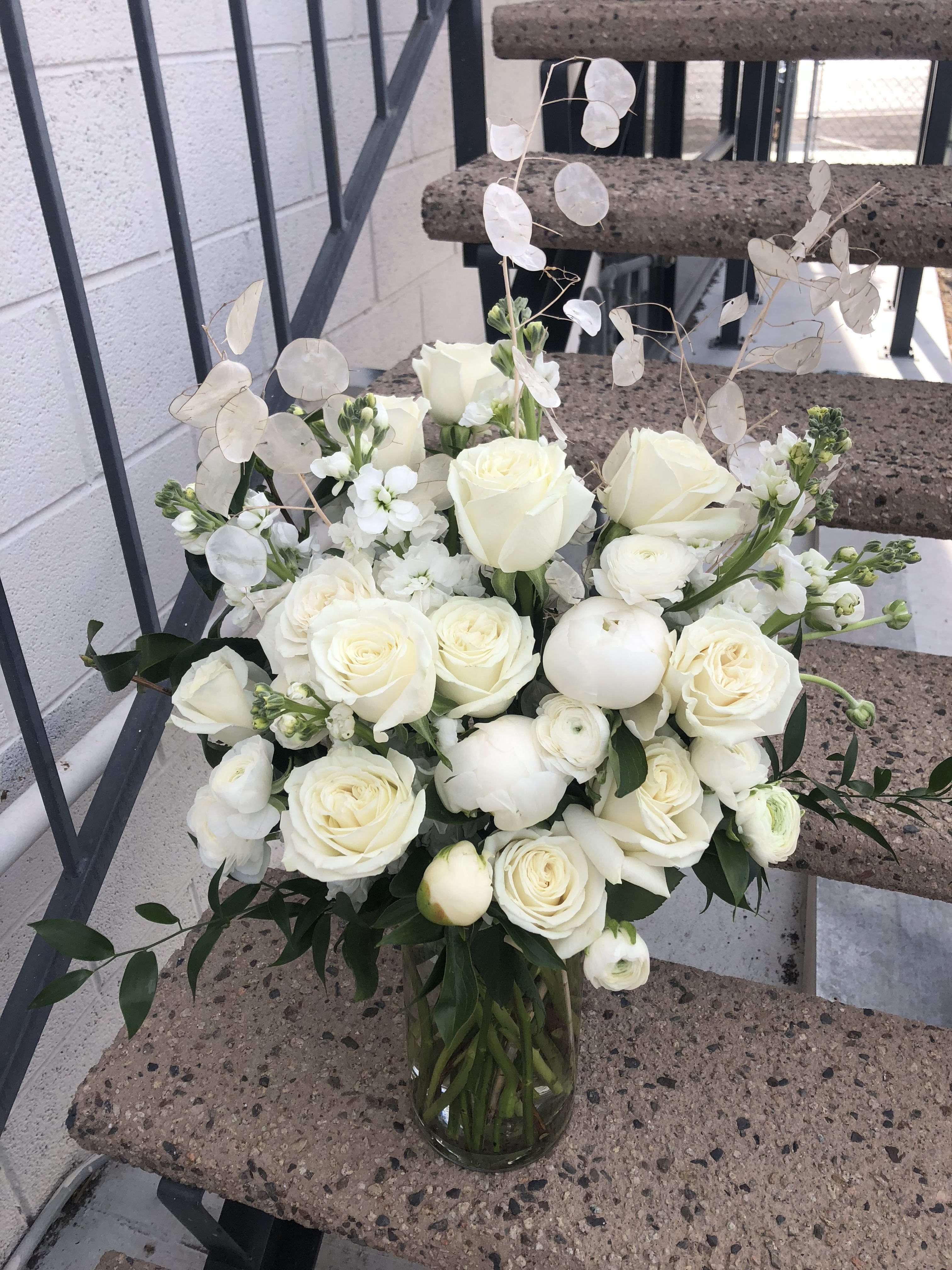 White rose bouquet in a glass vase with airy white filler flowers