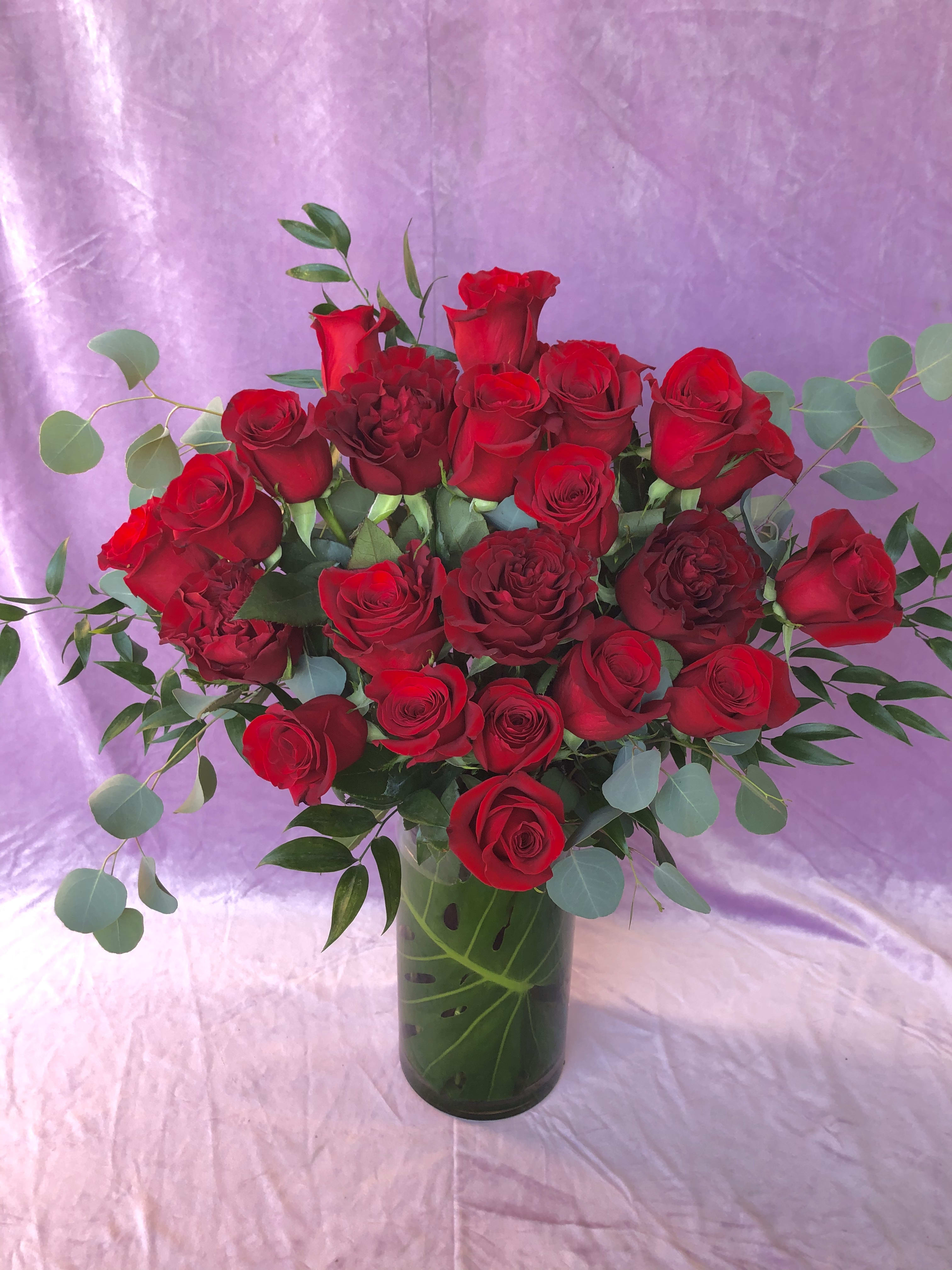 Bouquet of red roses in a glass vase with eucalyptus