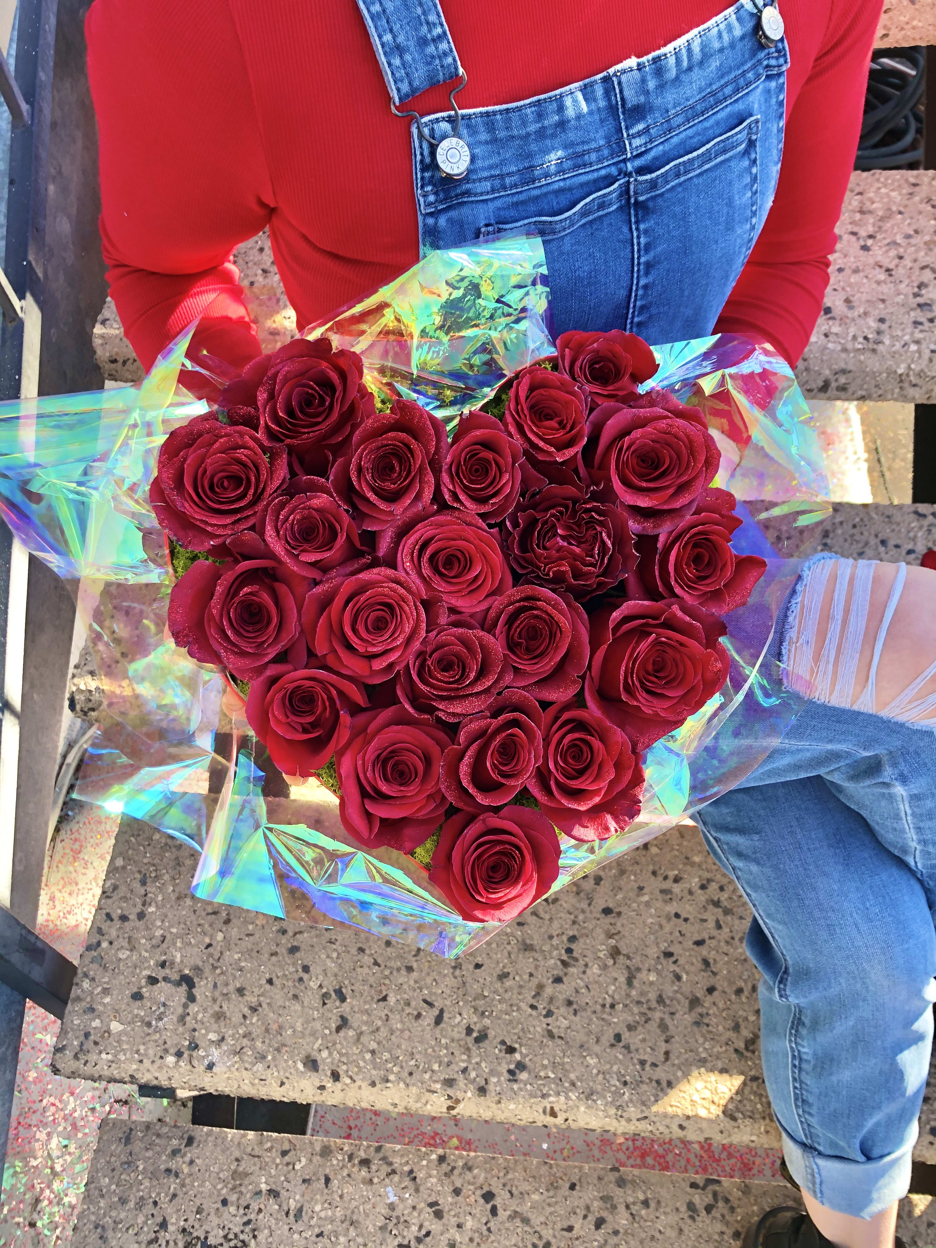 Heart-shaped bouquet of red roses wrapped in iridescent paper