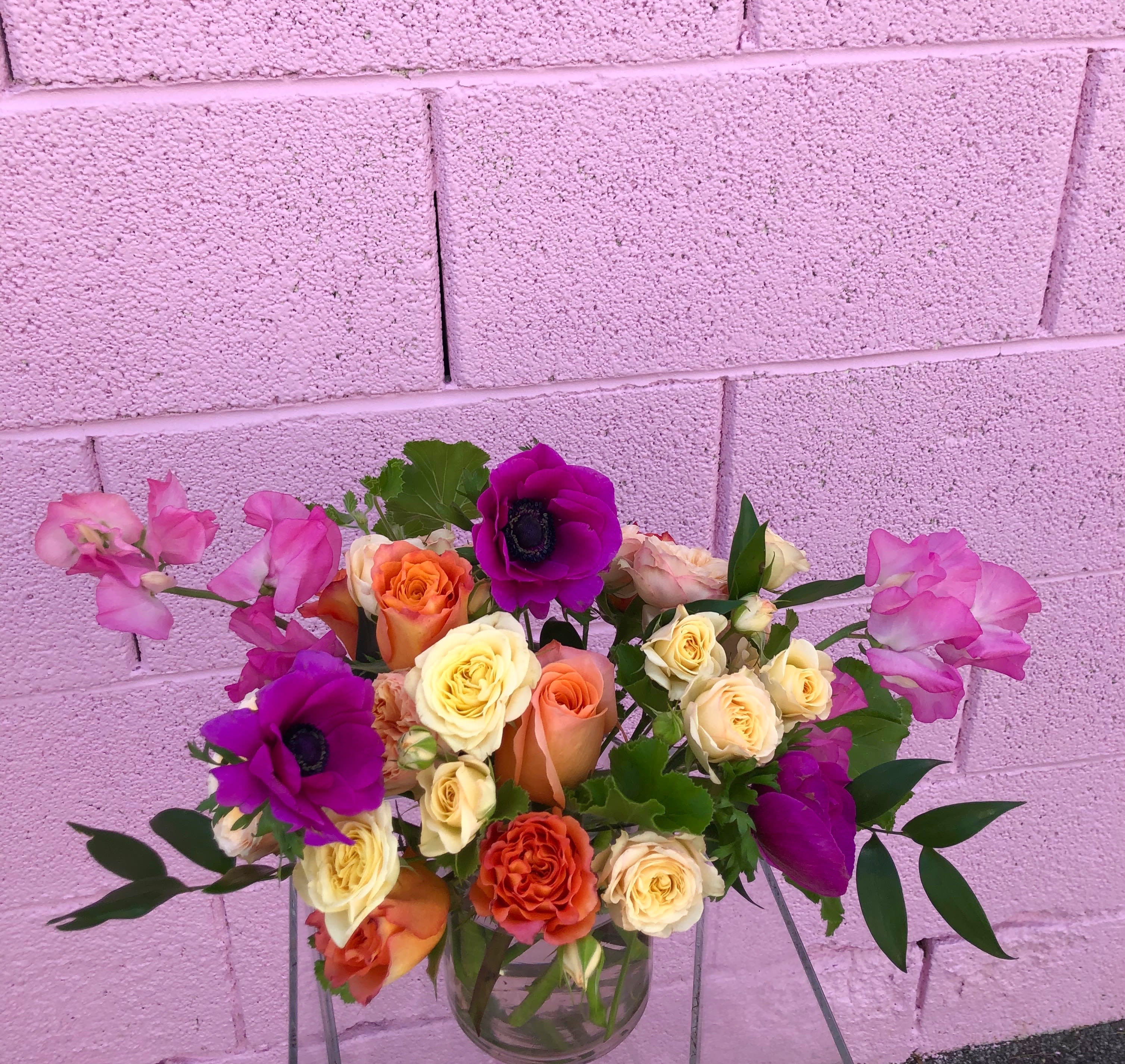 Mixed bouquet of roses and purple anemones in a clear glass vase
