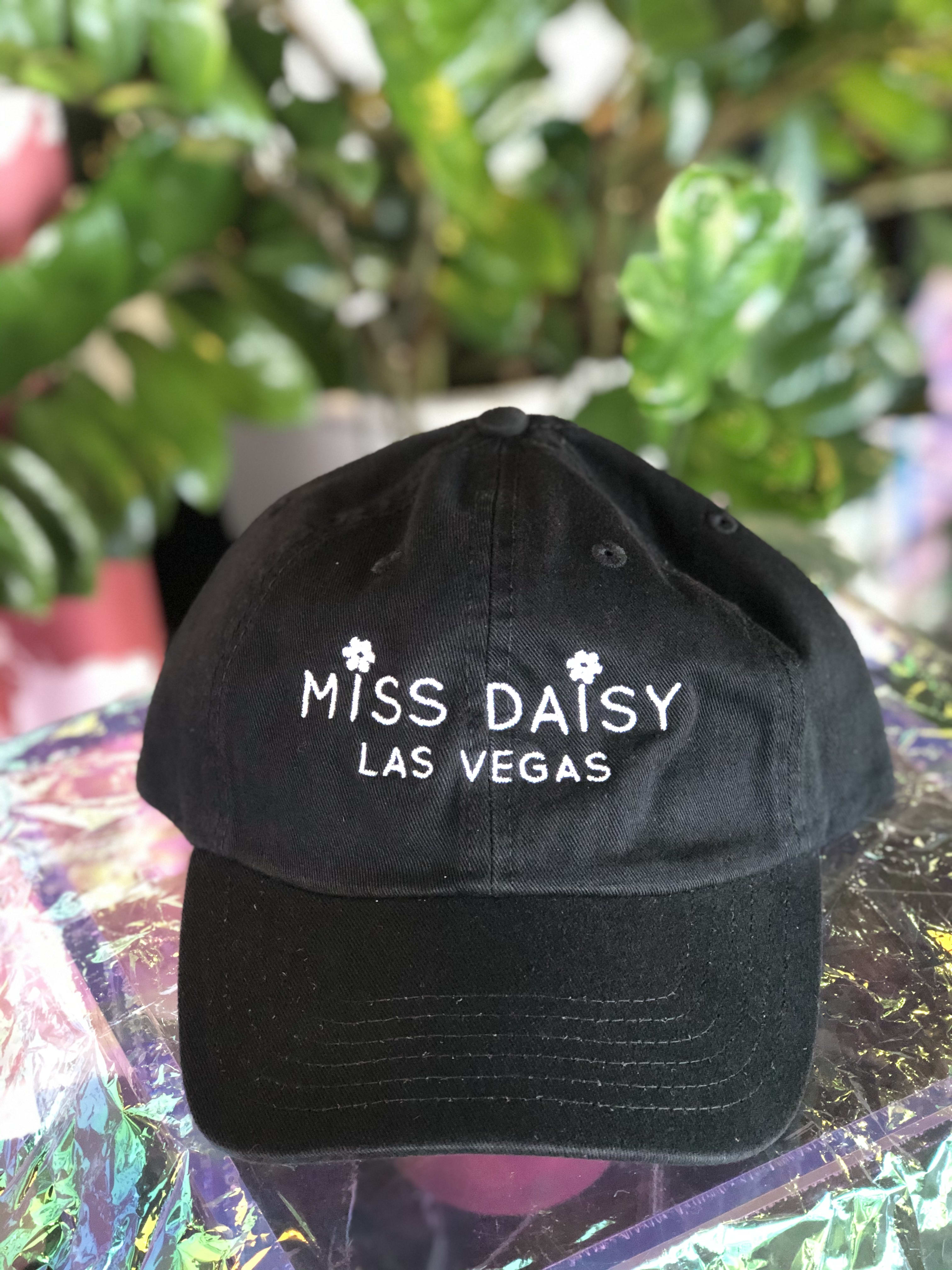 Black baseball cap with white "Miss Daisy Las Vegas" embroidery