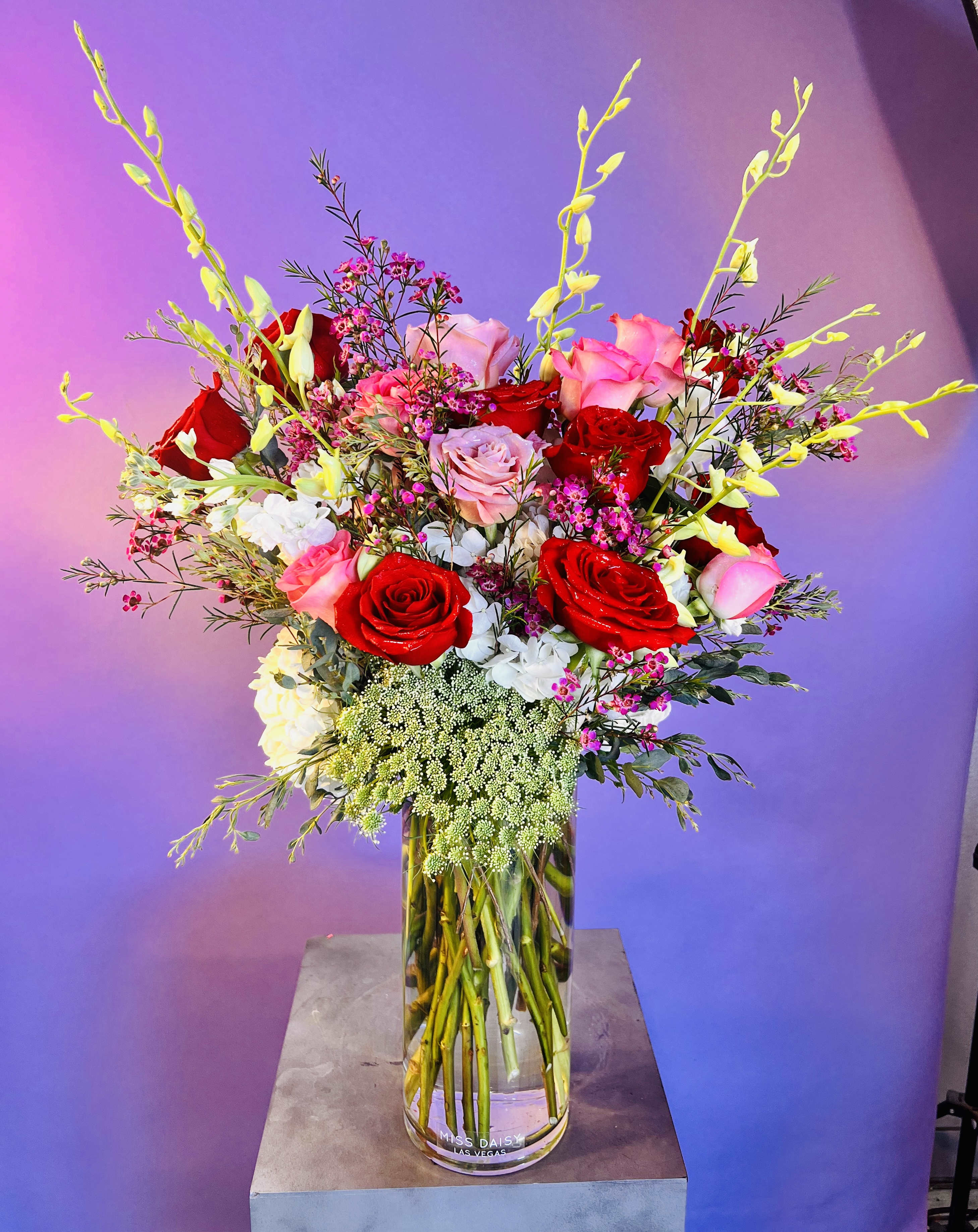 Te Quiero Mucho - Bursting with love and fresh blooms. This tall and full floral arrangement may include roses , orchids, hydrangea, and touches of wildflowers!