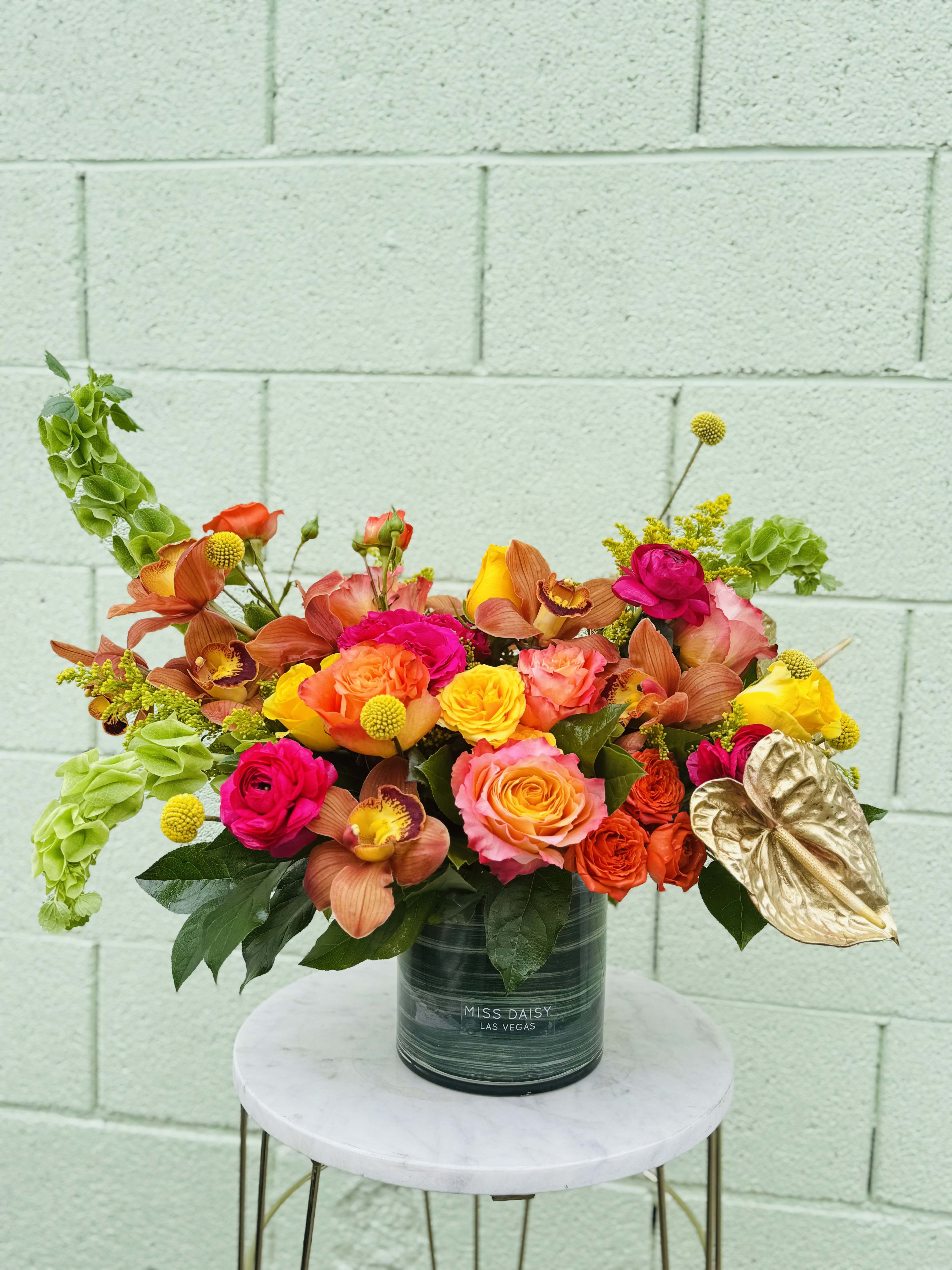 Bright mixed bouquet in a dark vase with orange, pink, and yellow blooms