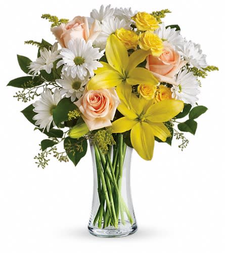 Bouquet of yellow lilies, peach roses, and white daisies in a clear glass vase