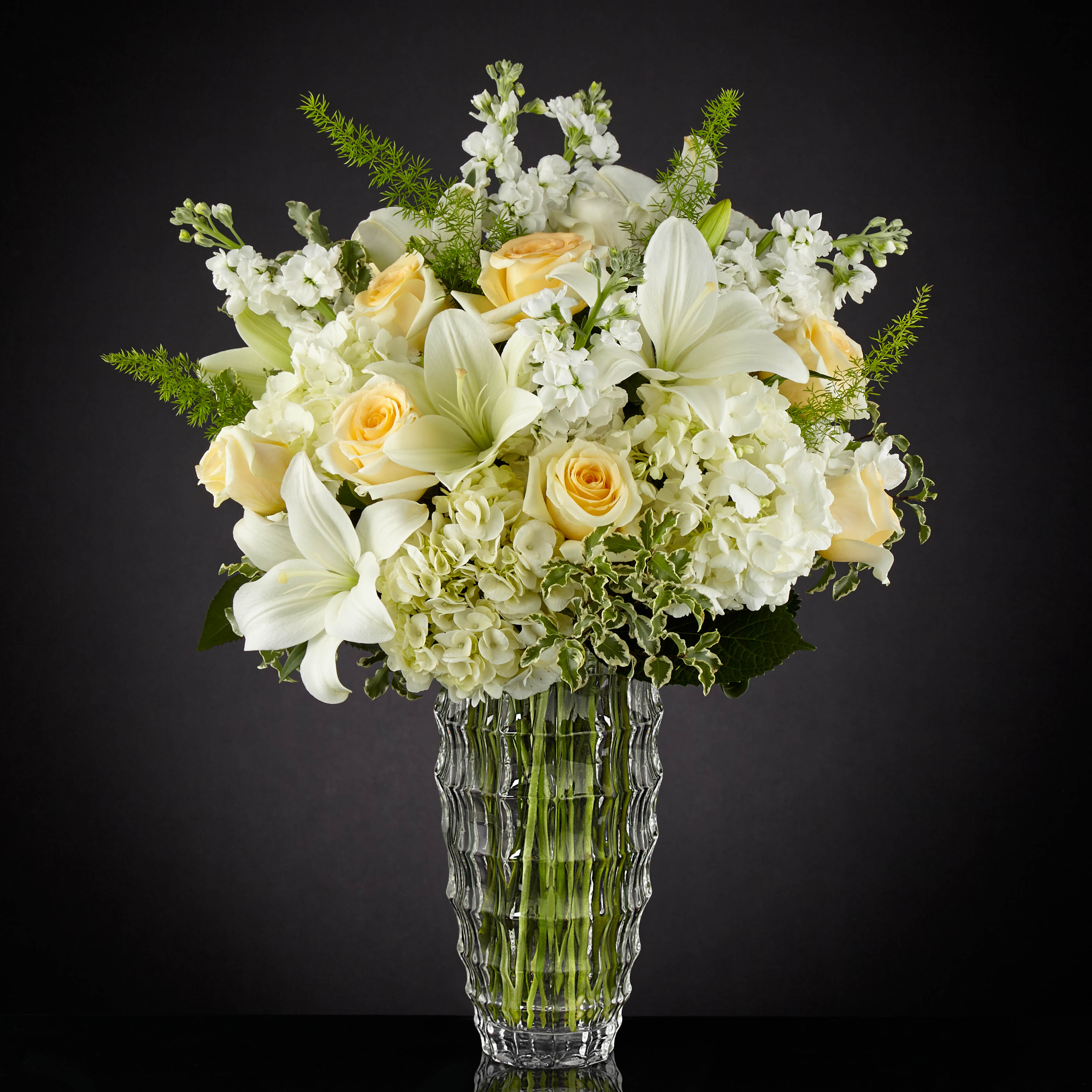 White and pale yellow floral arrangement in a clear glass vase