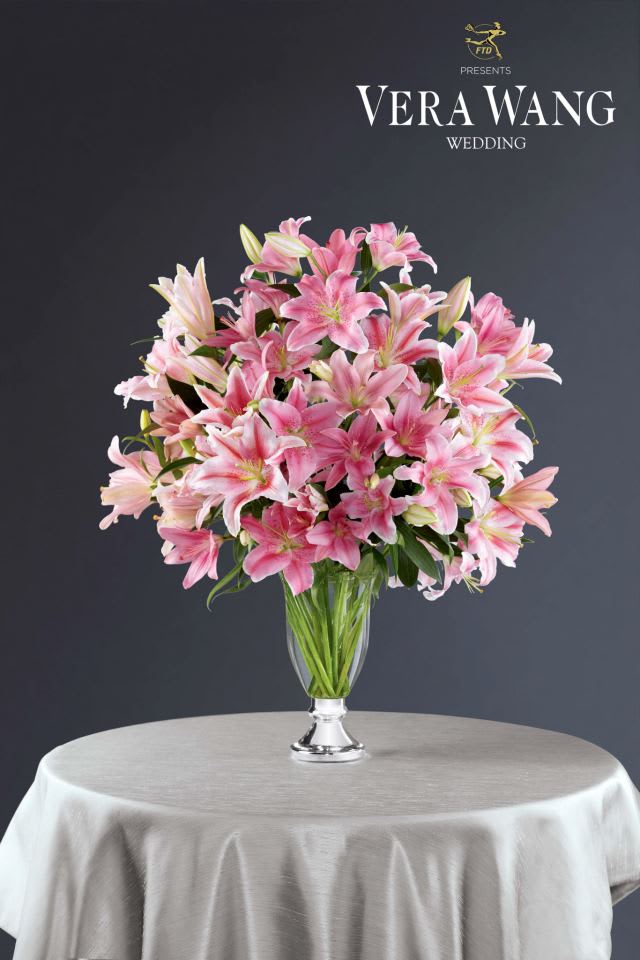 Pink lilies arranged in a clear glass vase on a table