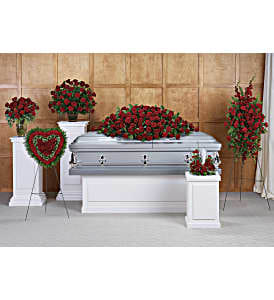 Casket surrounded by red rose funeral sprays and wreaths