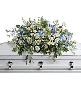 White and blue floral casket spray on a silver casket