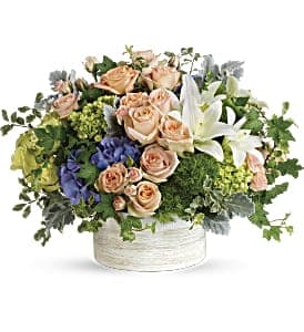 Peach roses and white lilies in a white basket arrangement