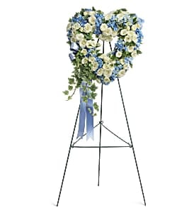 Heart-shaped floral wreath on a stand with blue and white flowers