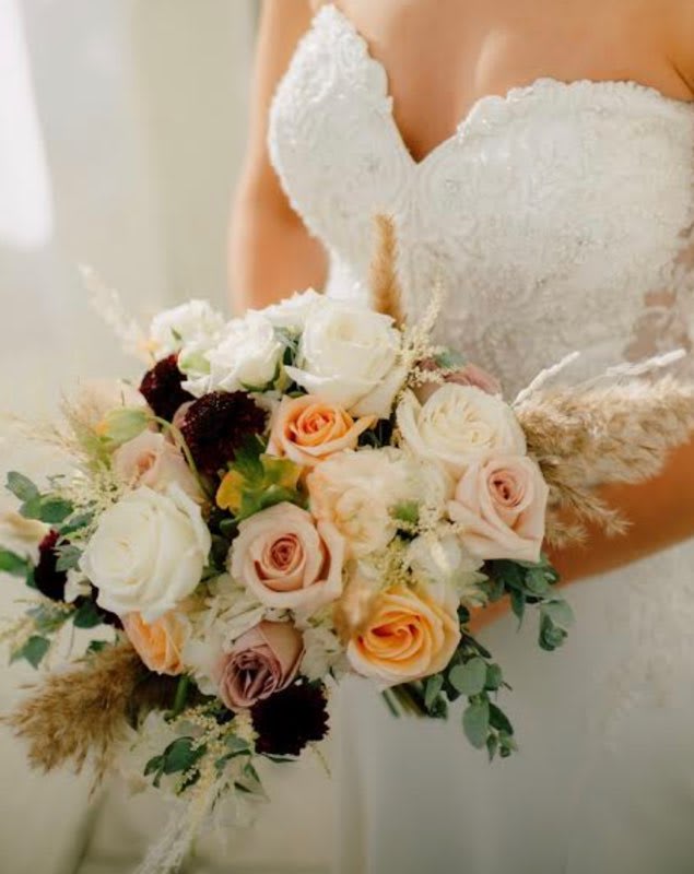 Bride holding a bouquet of white and peach roses