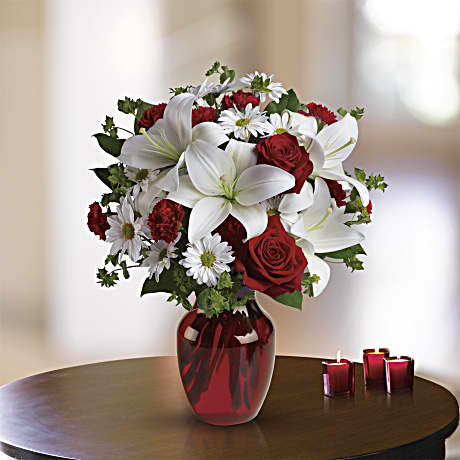 Bouquet of red roses and white lilies in a red glass vase