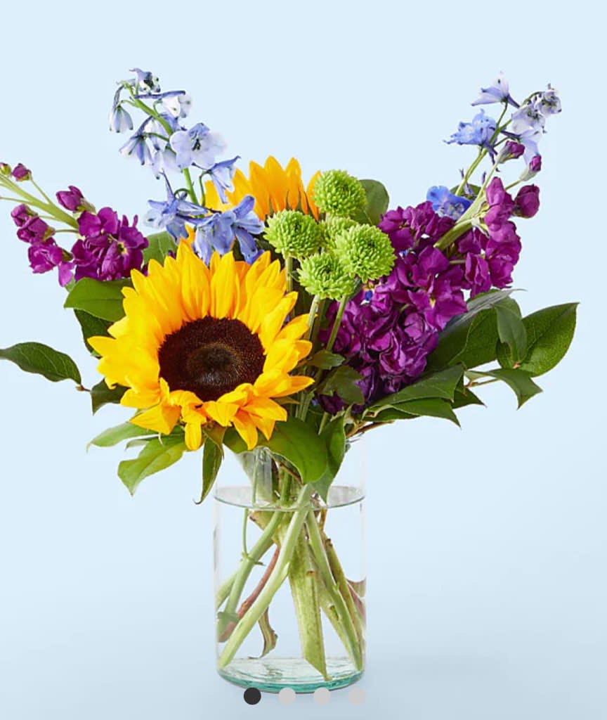 Sunflower bouquet with purple and blue flowers in a glass vase