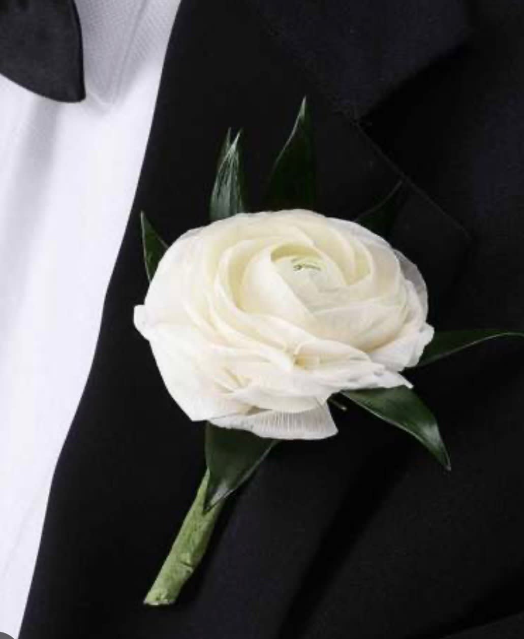 White flower boutonniere on a black suit jacket