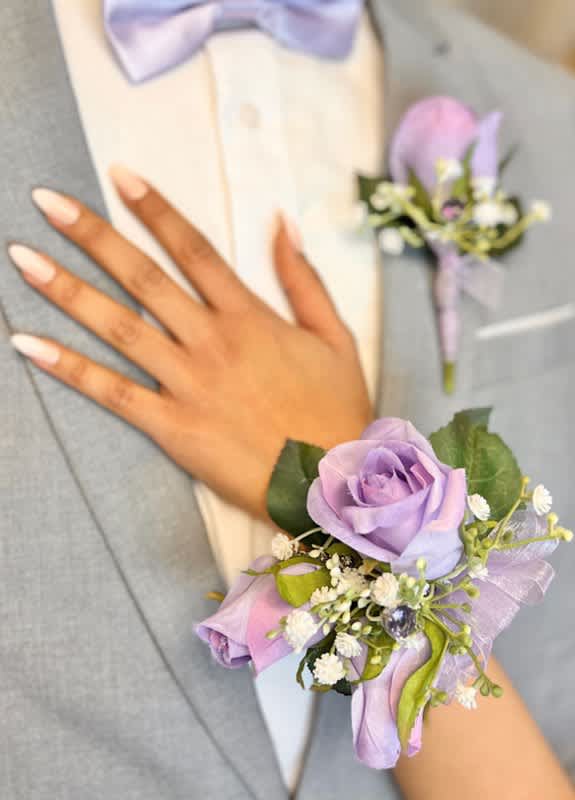Lavender rose corsage with small white flowers on a wrist