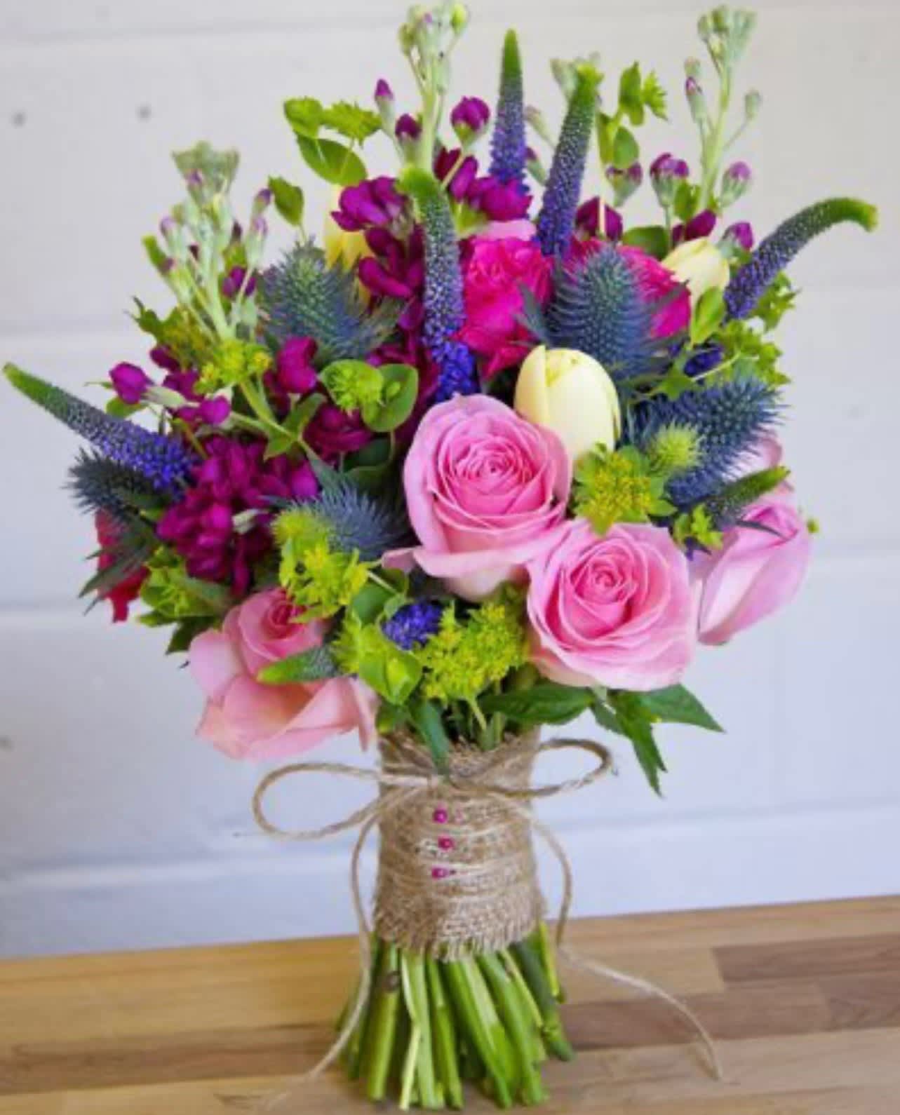Bouquet of pink roses and purple flowers wrapped with twine