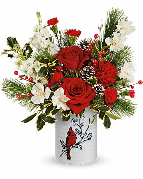 Red roses and white flowers in a decorative vase with pine accents