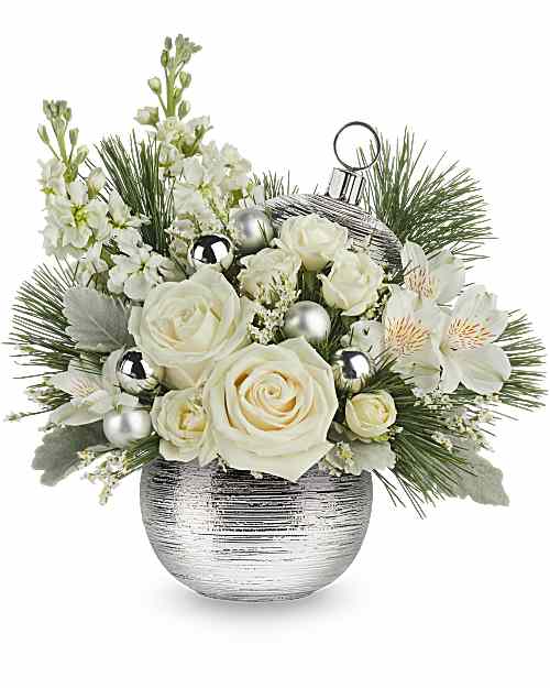 White roses and blossoms in a silver vase with pine accents and ornaments