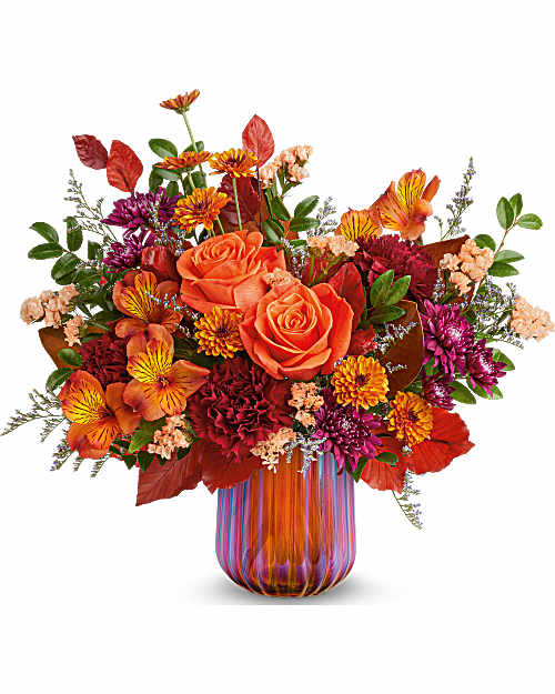Orange roses and mixed autumn flowers in a striped glass vase