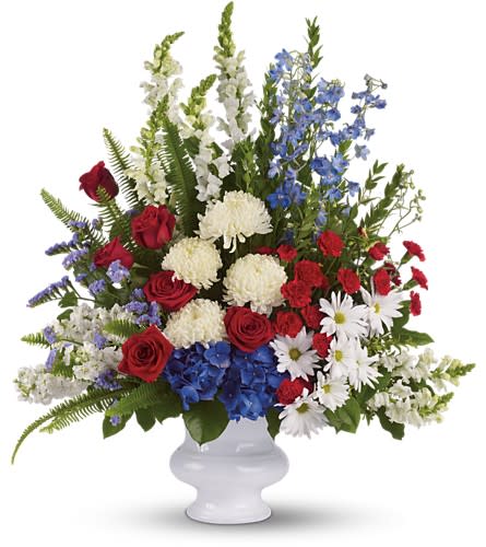 Mixed bouquet of red, white, and blue flowers in a white vase