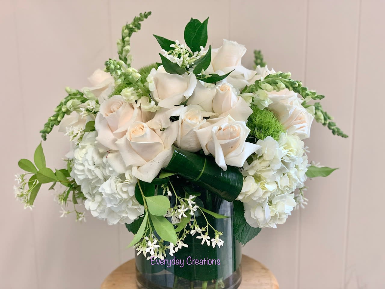 White roses and hydrangeas arranged in a glass vase