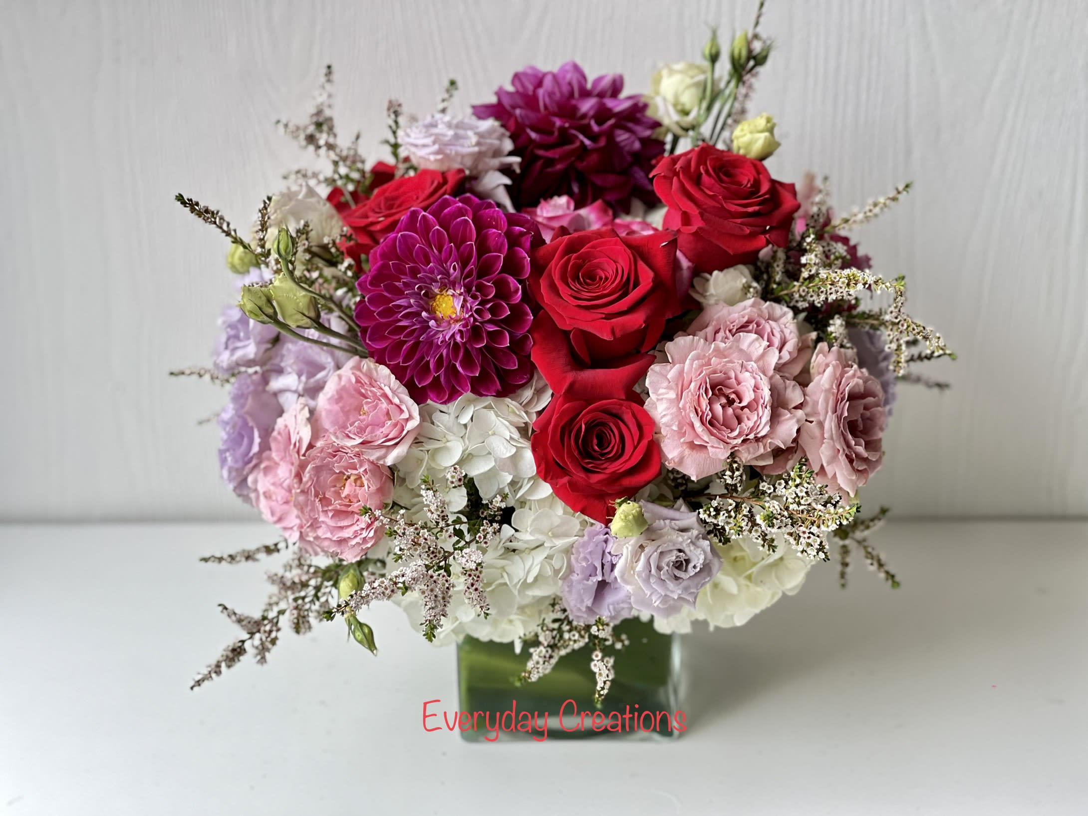Mixed bouquet of red, pink, and white flowers in a glass vase
