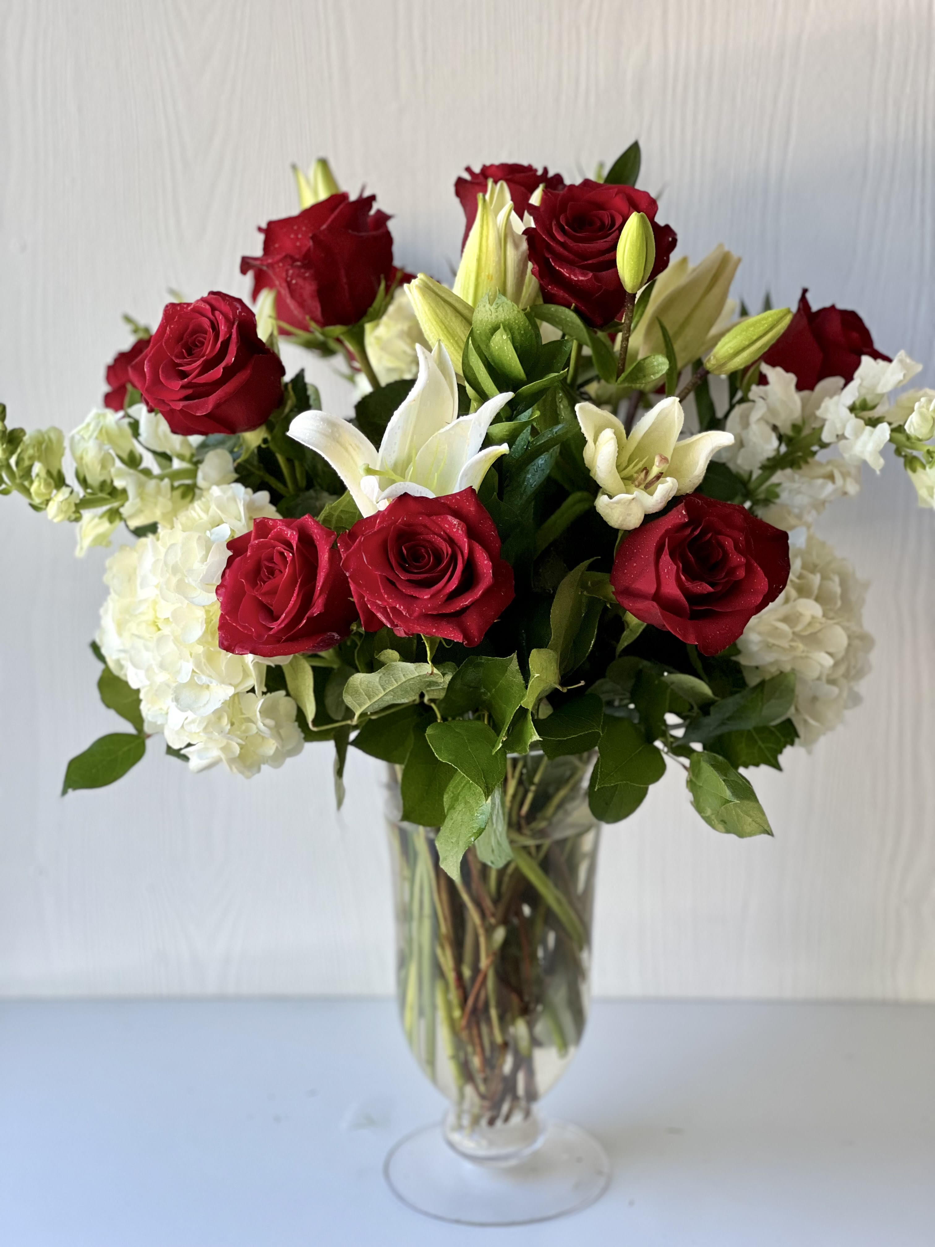 Red roses and white lilies arranged in a clear glass vase