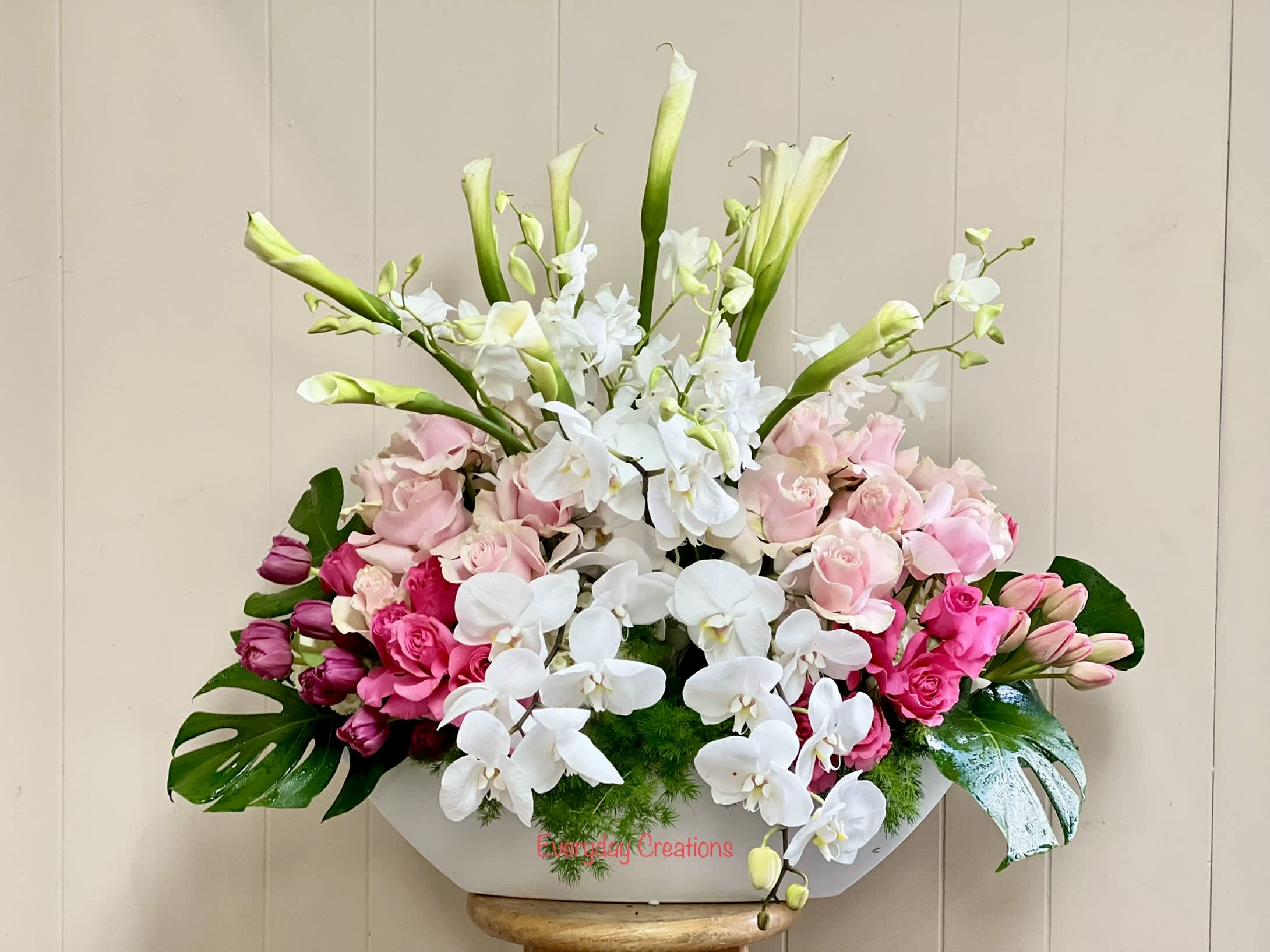 Pink roses and white orchids in a white container