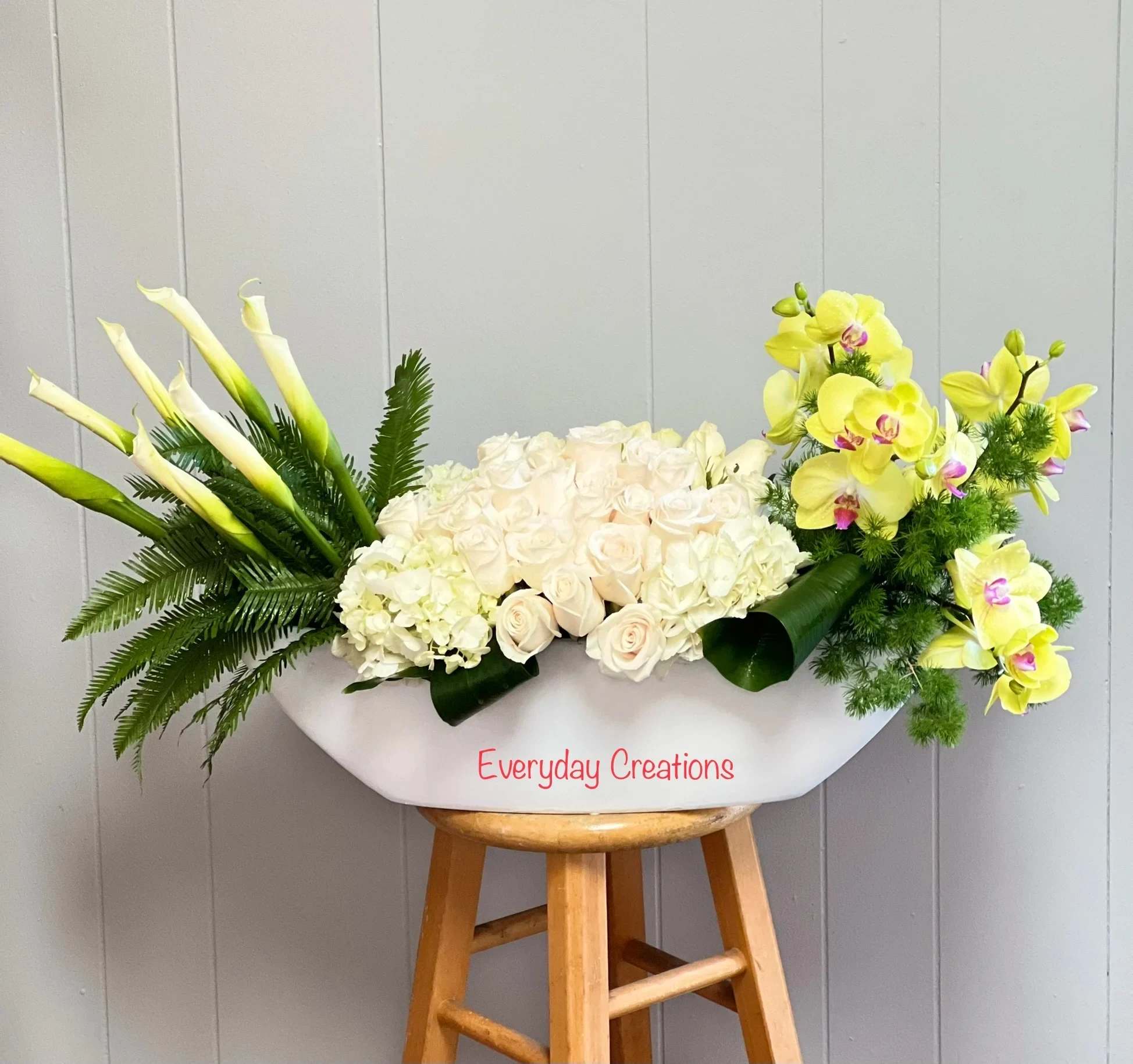 White floral arrangement with calla lilies, roses, hydrangea, and yellow orchids