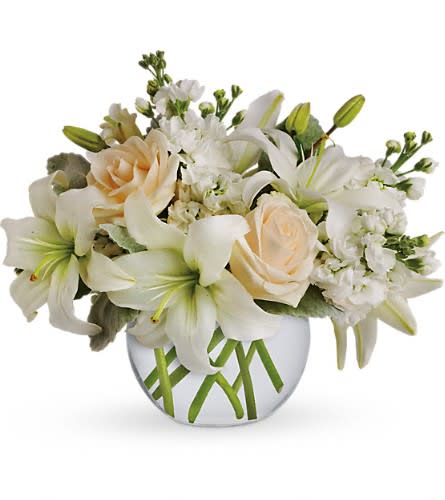 White lilies and pale peach roses in a round glass vase