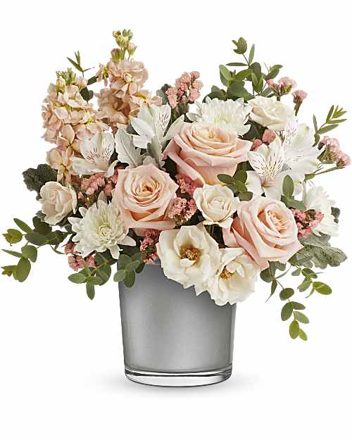 Radiant Blossoms - Radiating peace and energy, this unforgettable arrangement of soft peach and crème blooms in a shimmering silver cylinder is a stylish gift for any special occasion. Elevate any space with the exquisite combination of peach roses, crème spray roses, ivory alstroemeria, stock, and white cushion spray chrysanthemums. Enhanced with statice, dusty miller, and parvifolia eucalyptus, all showcased in Teleflora's Silver Polished Gem Cylinder.