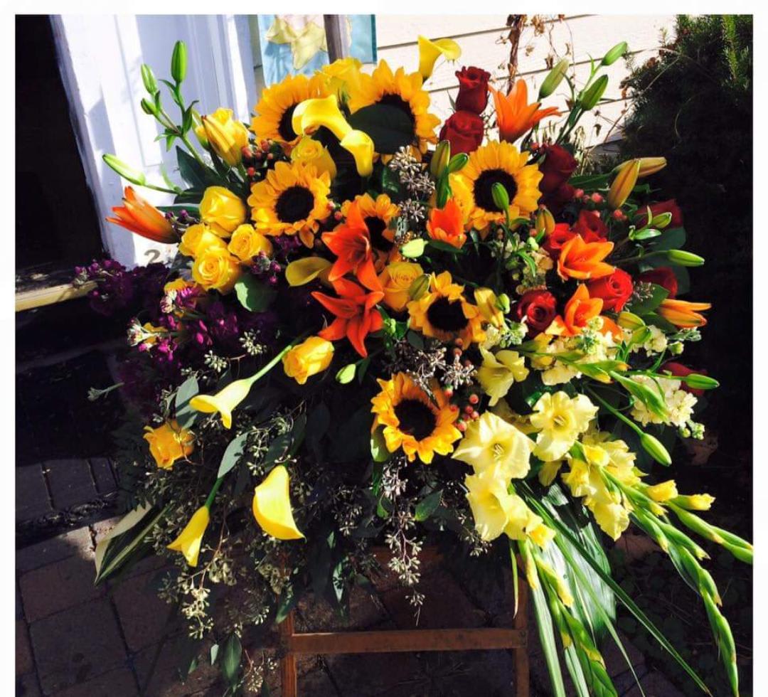 Large mixed floral spray with sunflowers, roses, lilies, and calla lilies