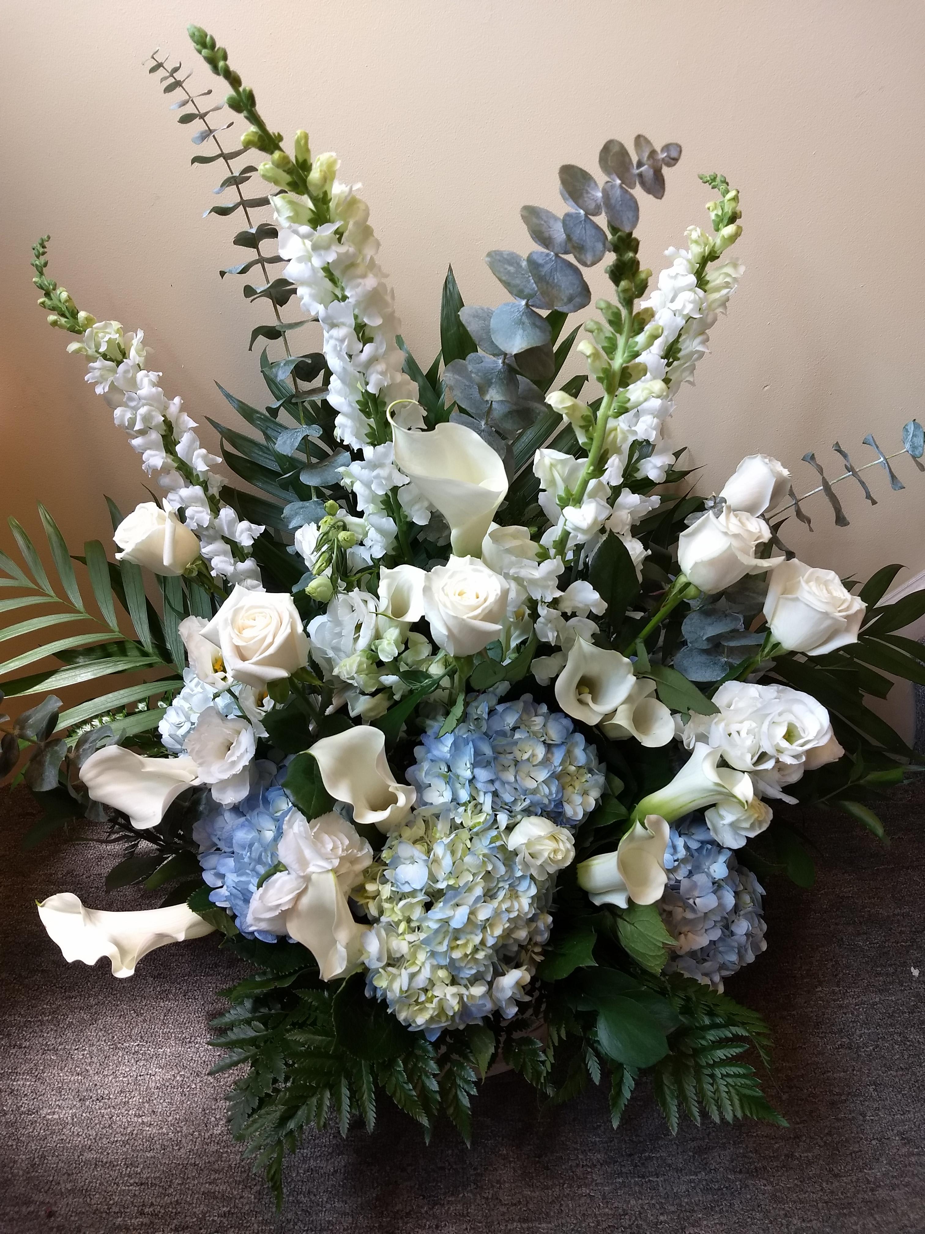 White roses, calla lilies, and blue hydrangeas in a large arrangement
