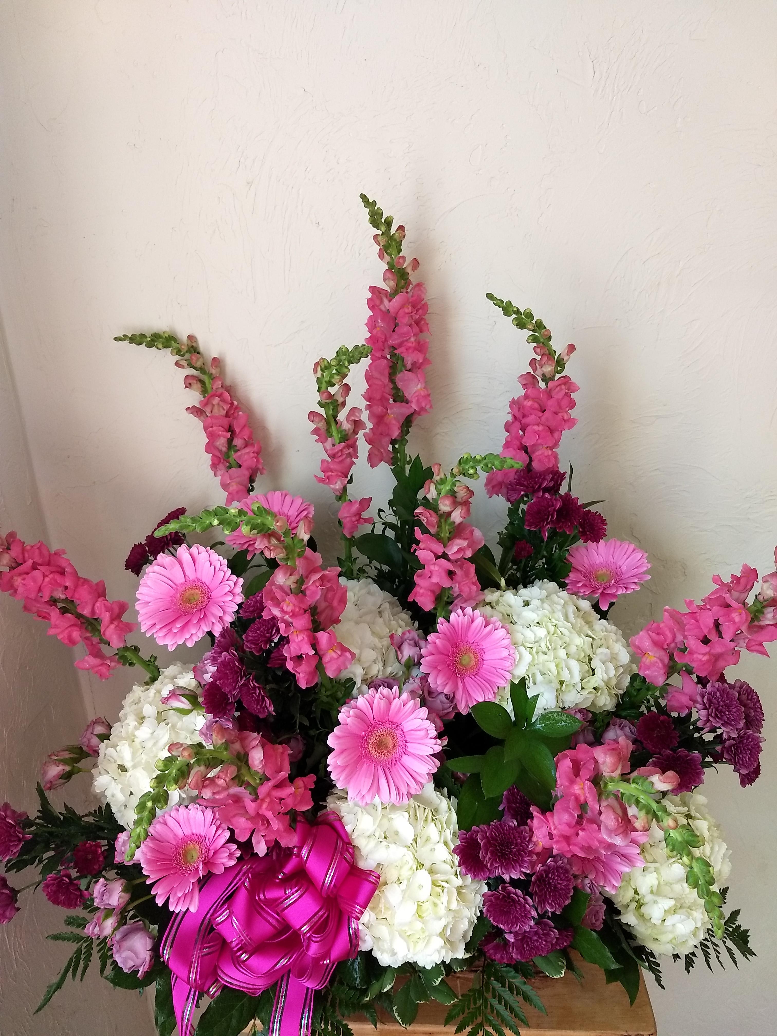 Pink and white floral arrangement with gerbera daisies and snapdragons in a basket