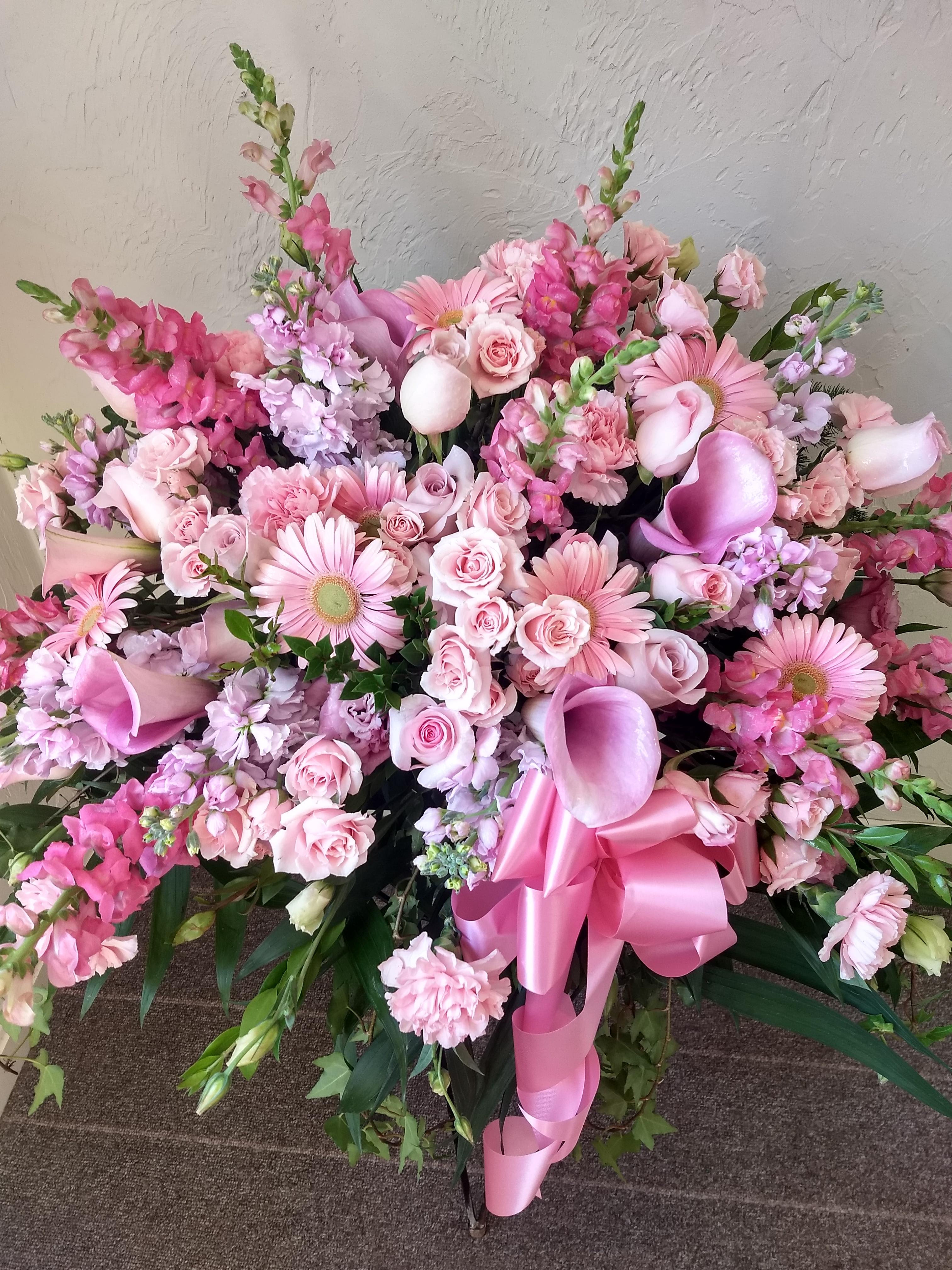Large pink floral spray with roses, gerbera daisies, calla lilies, and a ribbon bow