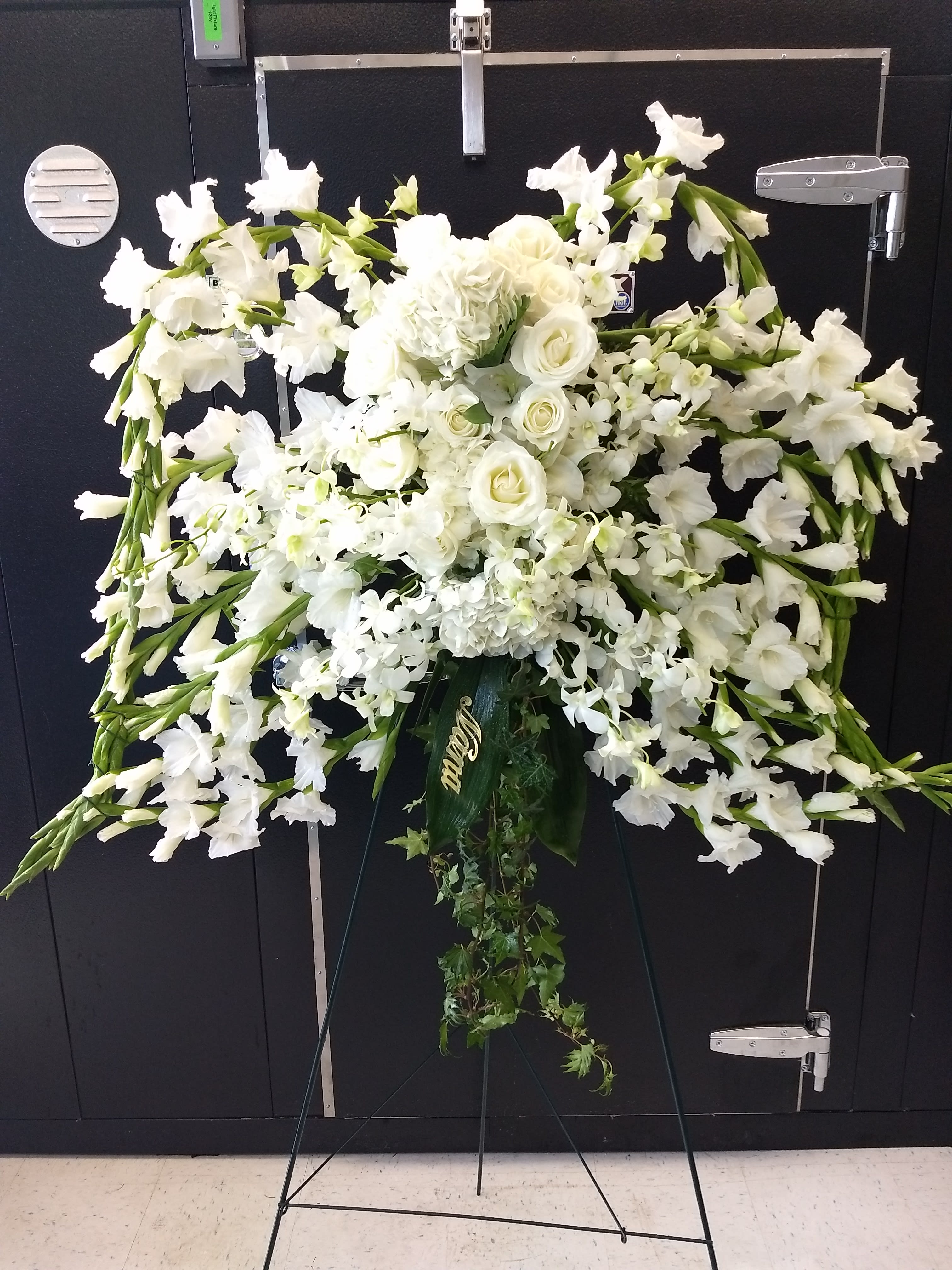 White funeral spray with roses and orchids on a standing easel