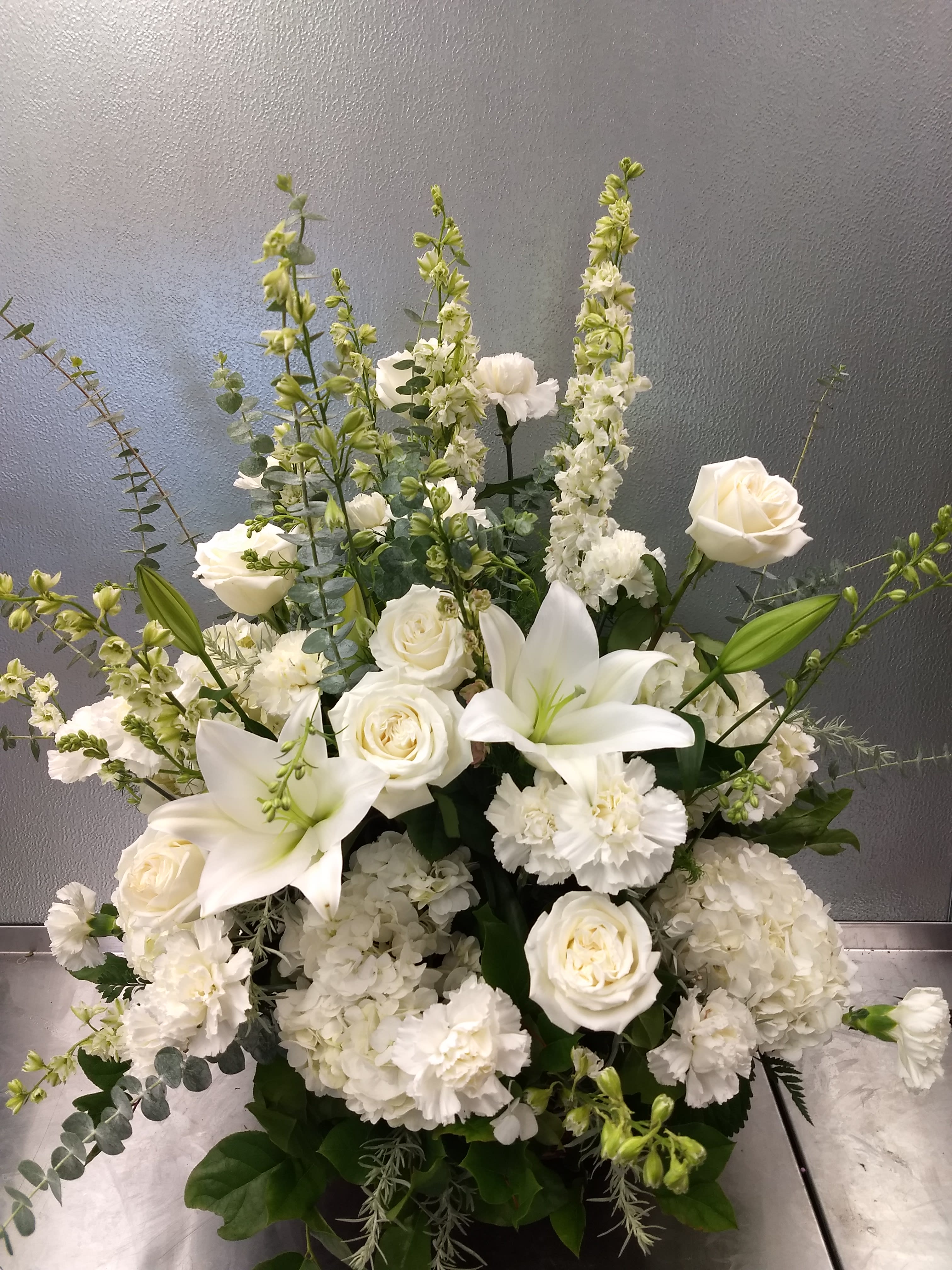 White roses and lilies arranged with tall white blooms in a vase