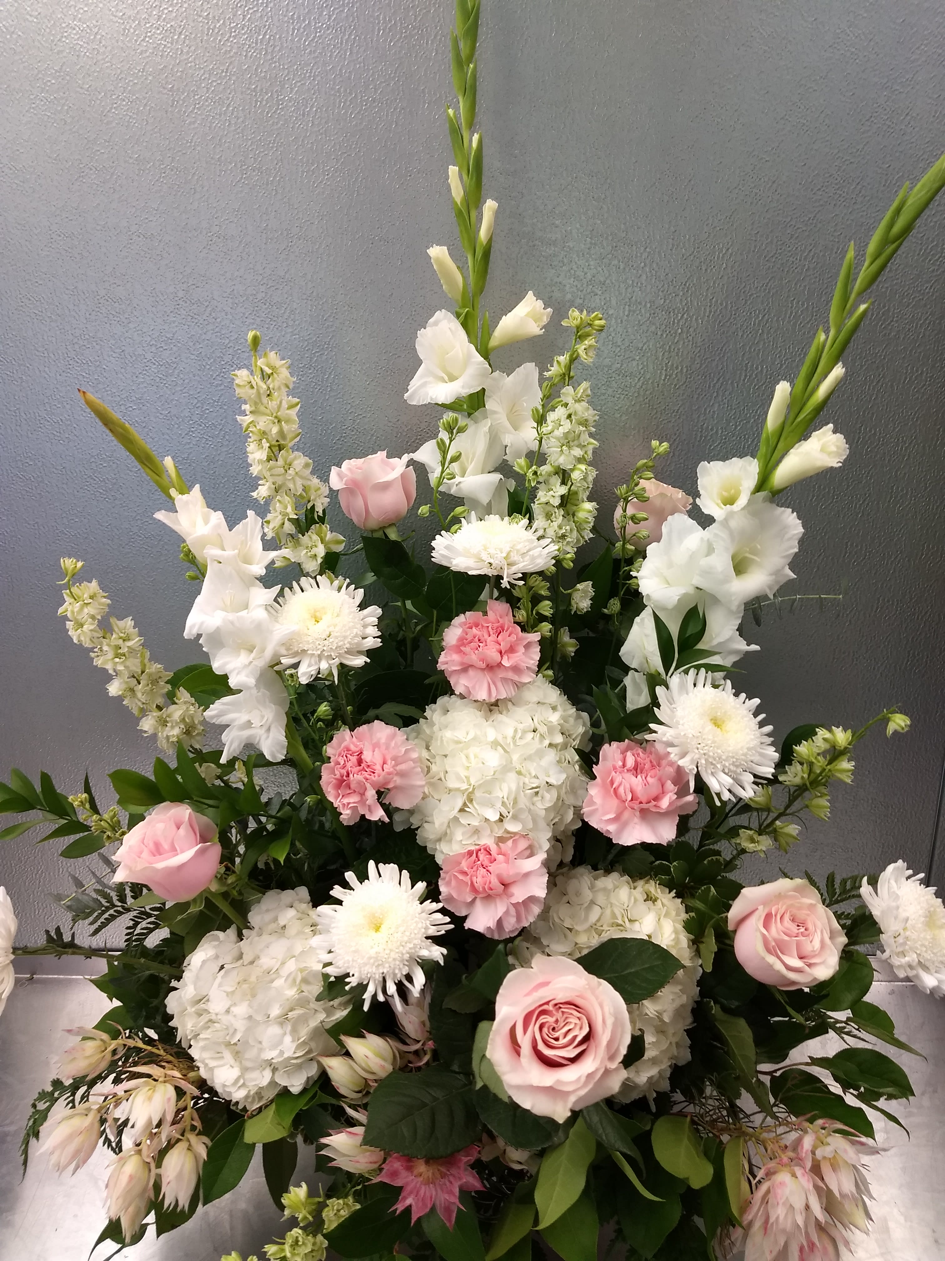 Pink roses, white hydrangeas, and white daisies in a tall arrangement