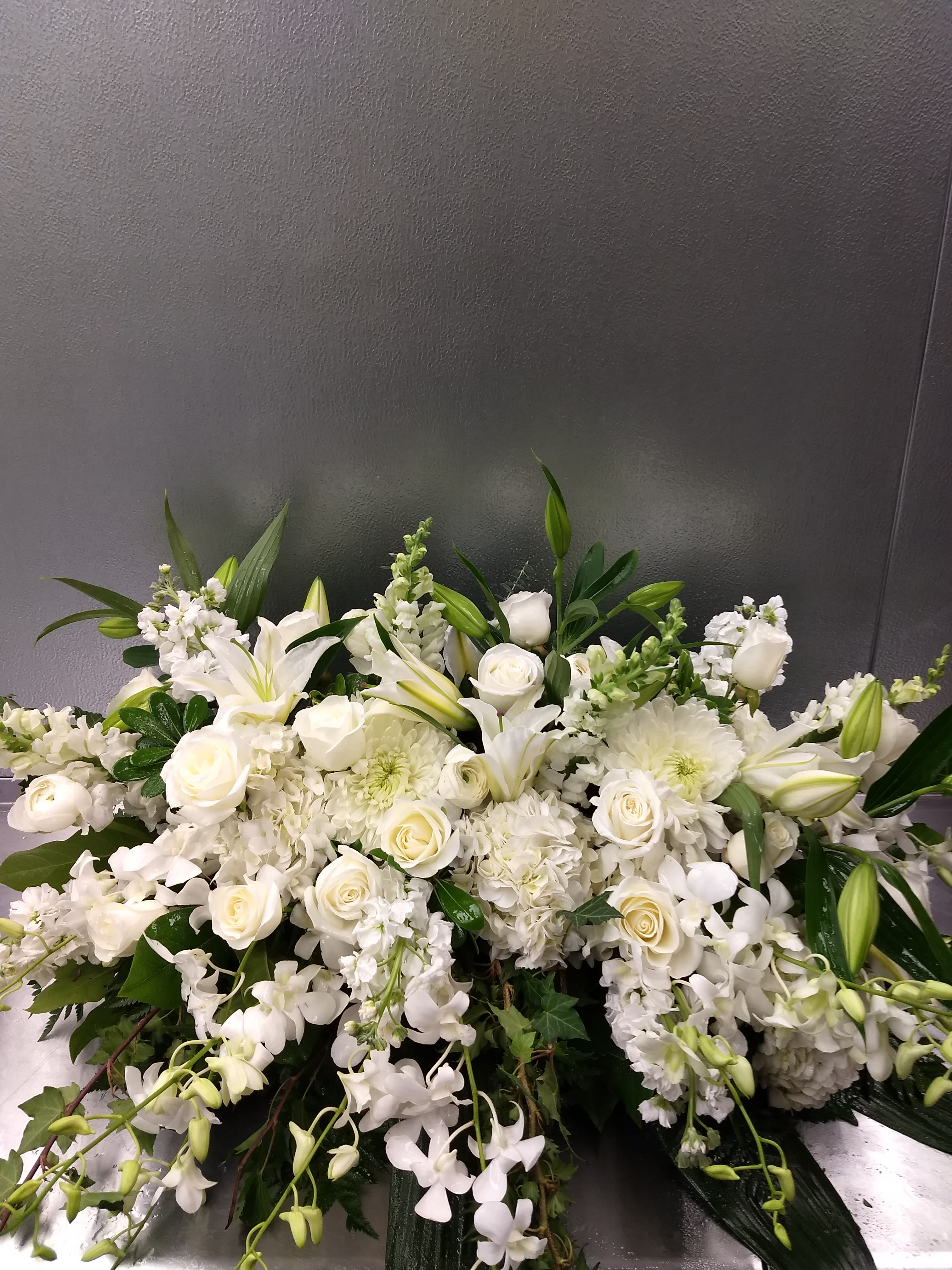 Large white floral arrangement with roses, lilies, and orchids