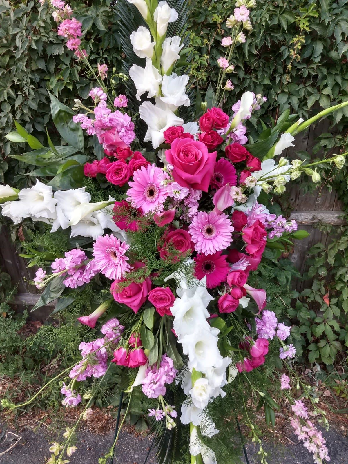 Large standing floral spray with pink roses, gerbera daisies, and white gladiolus