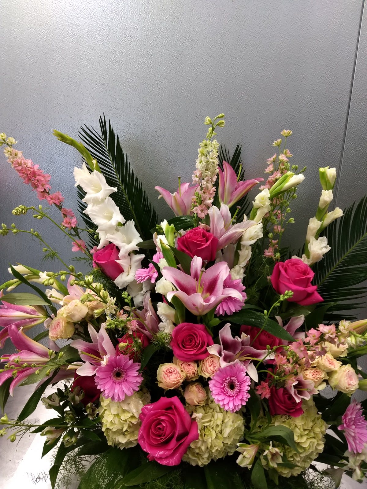 Large pink and white floral arrangement with roses, lilies, and gerbera daisies