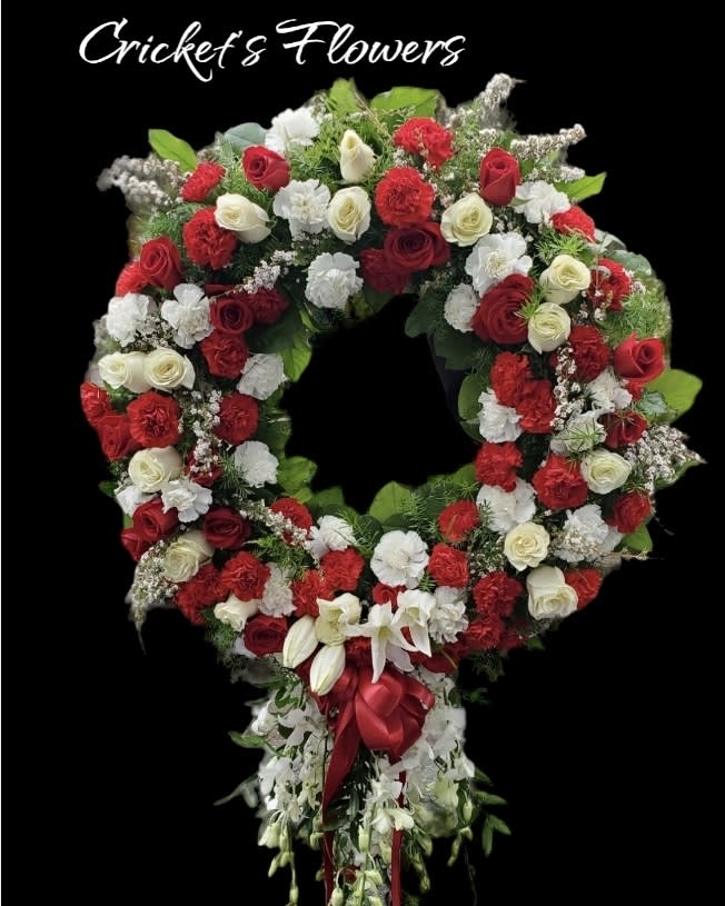 Large red and white floral wreath with a cascading ribbon tail