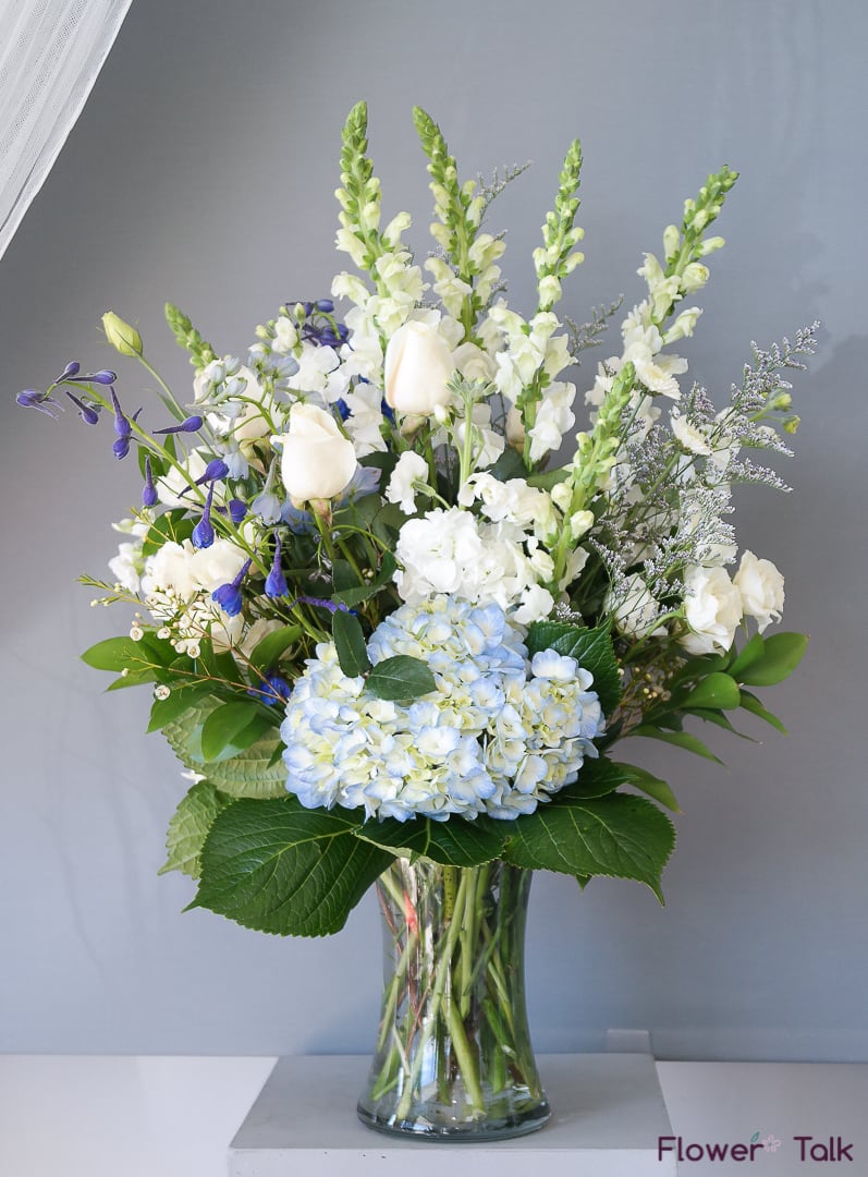White and blue floral arrangement in a glass vase