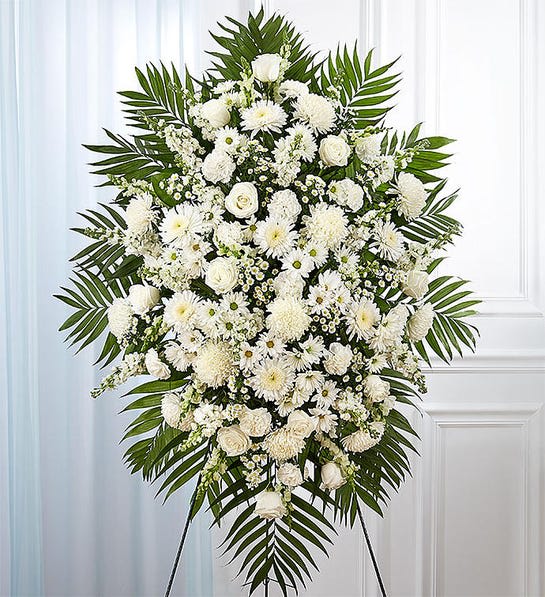Large white funeral spray with mixed blooms and palm fronds