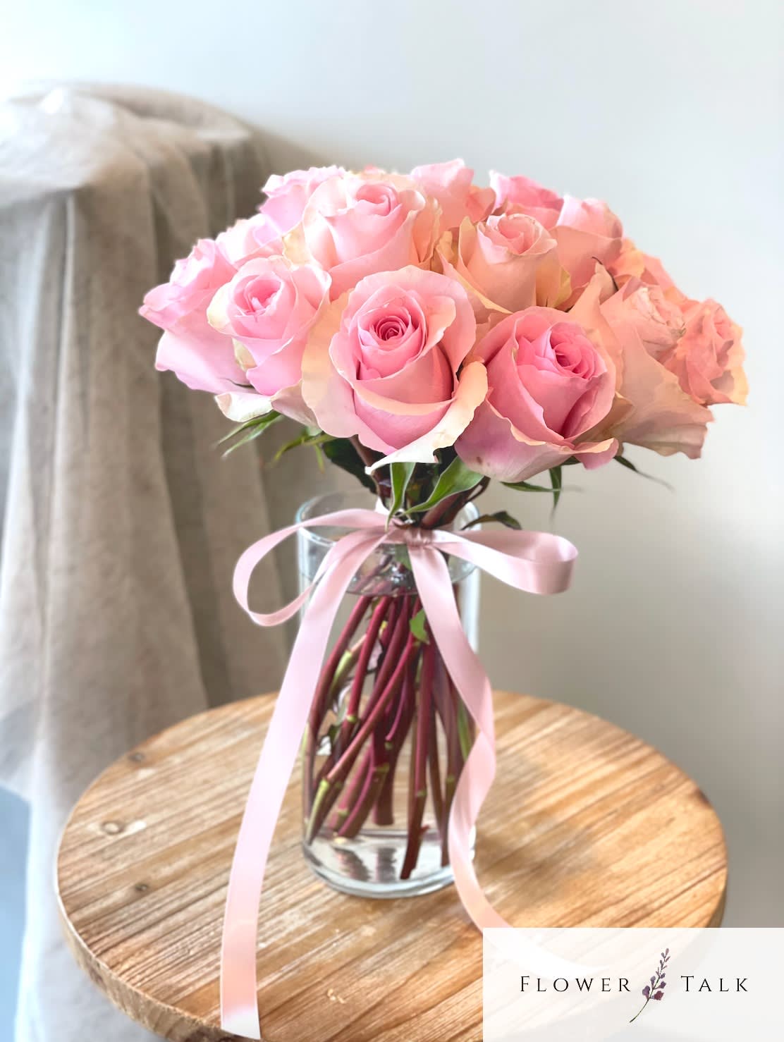 Pink rose bouquet in a clear glass vase with a pink ribbon