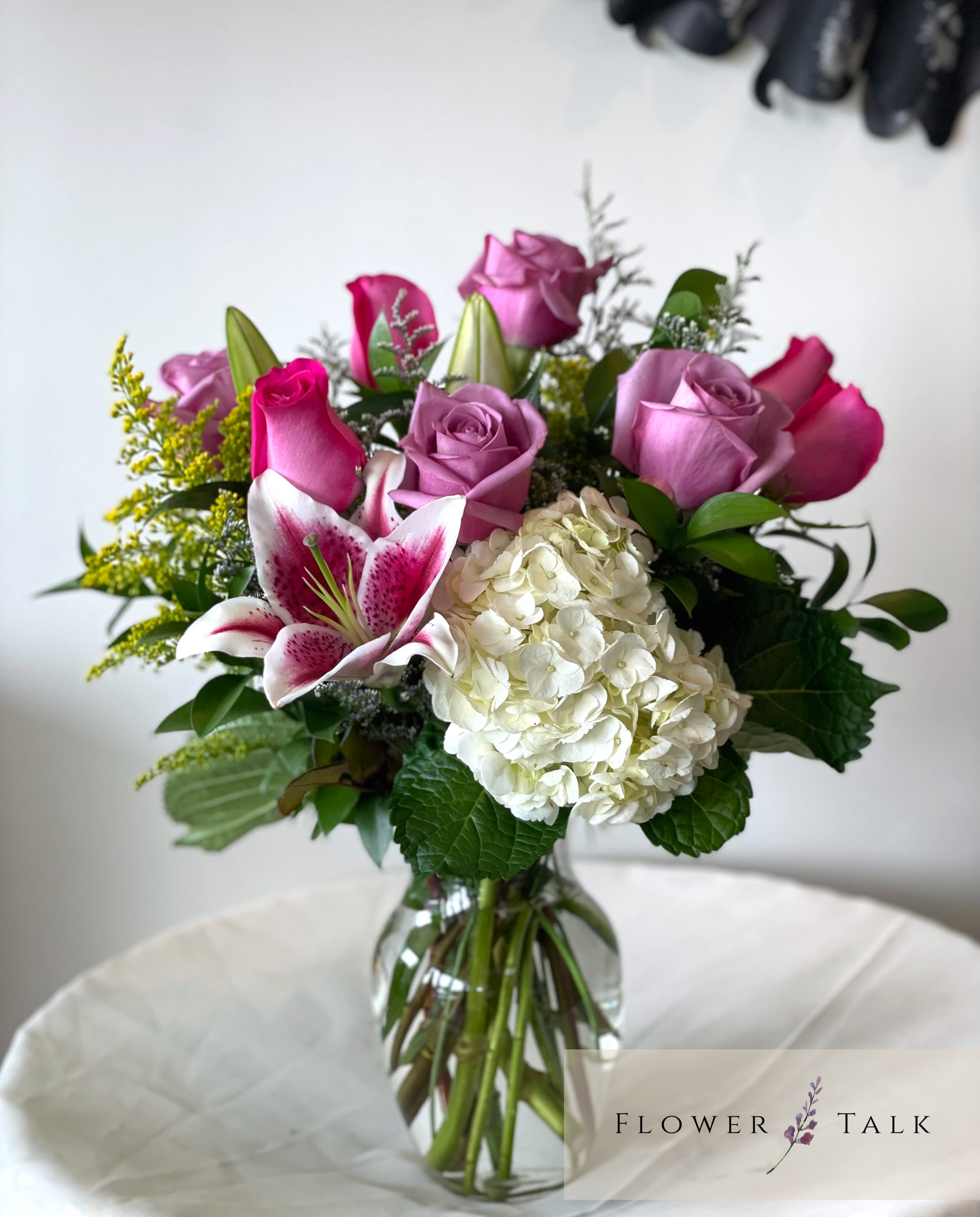 Stella Bouquet  - A mix of purple and pink roses, pop of stargazer and hydrangea in a vase.