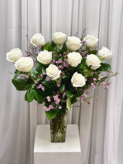 White roses and pink filler flowers in a clear glass vase